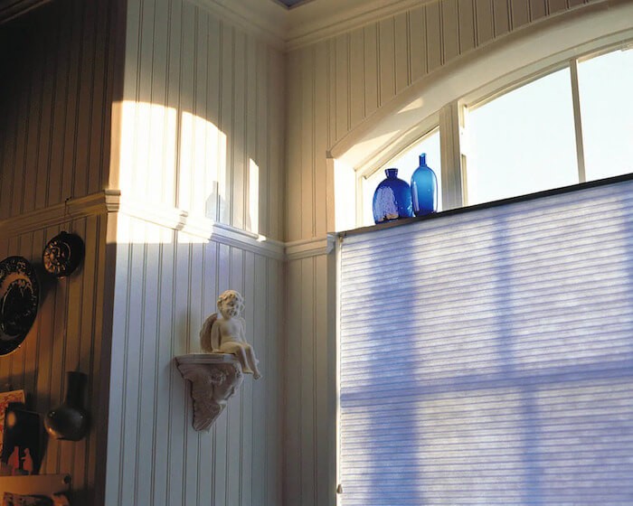 top half of cellular blinds are down, letting in sunlight from large window.