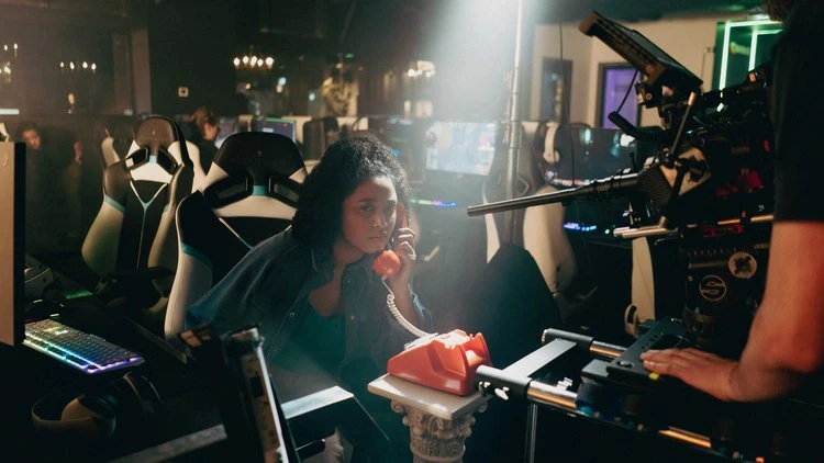 An actor in front of a camera being filmed inside a computer room