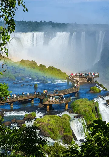 Passarela panorâmica nas Cataratas do Iguaçu, com quedas d’água, vegetação exuberante e visitantes observando a paisagem