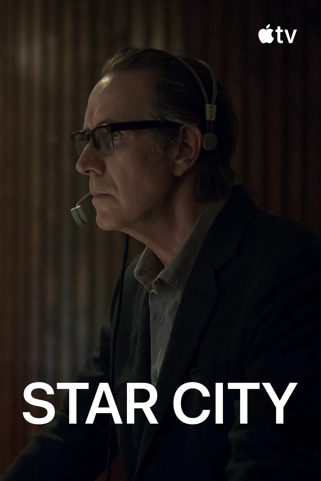A man wearing glasses and a headset appears thoughtful in a dimly lit, wood-paneled room, with the text "Star City" and an Apple TV logo at the top right corner.