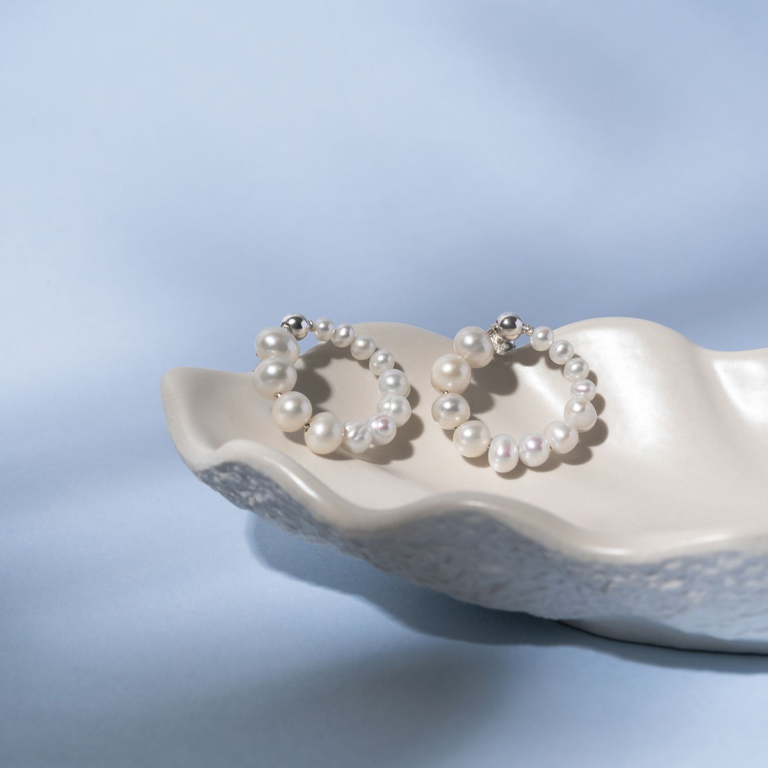 White pearl earrings with a blue background