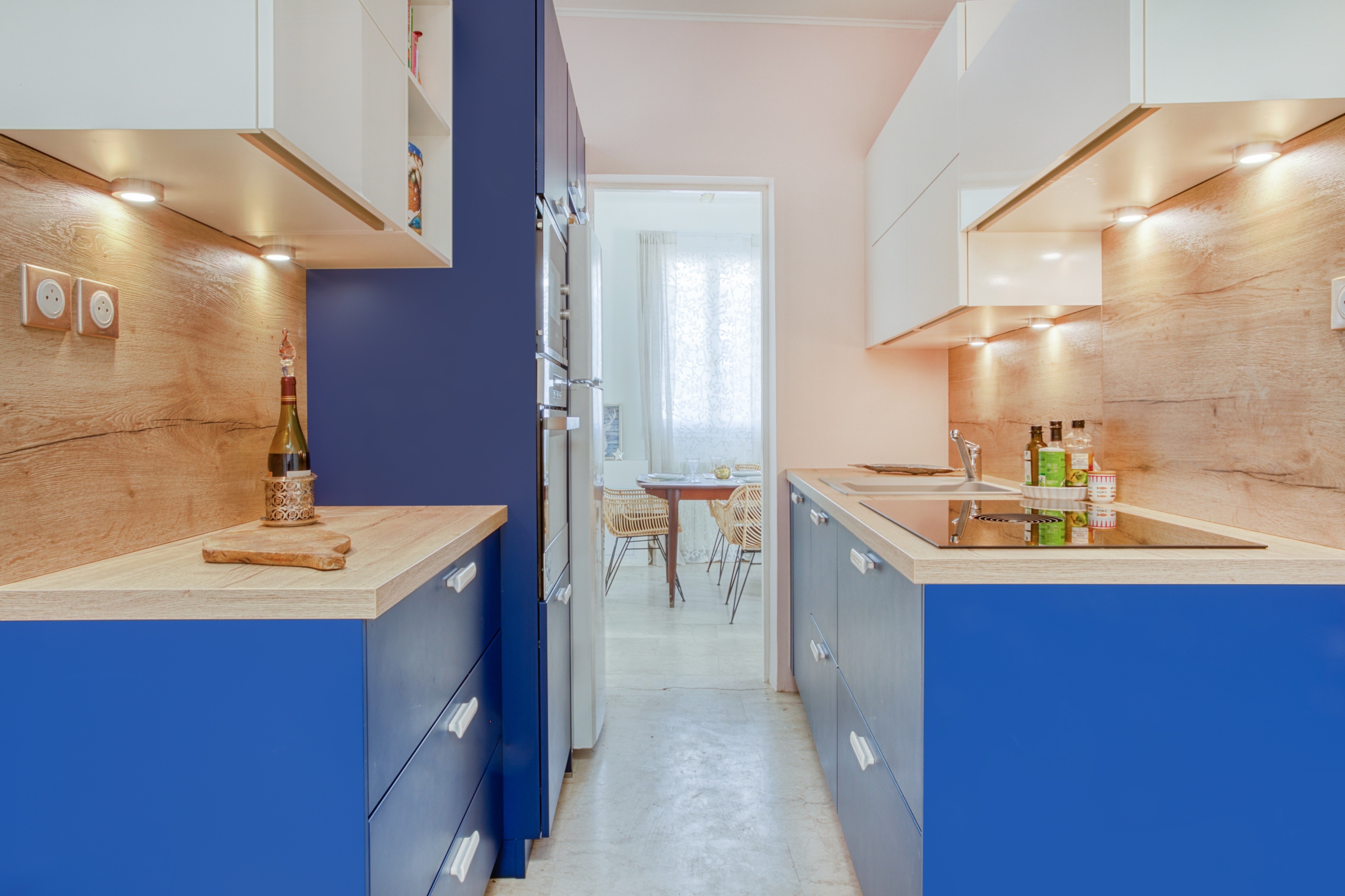 Transformation cuisine 77 avec armoires inférieures bleues, comptoirs bois et armoires supérieures blanches, éclairage sous armoire, rénovation 3 pièces.