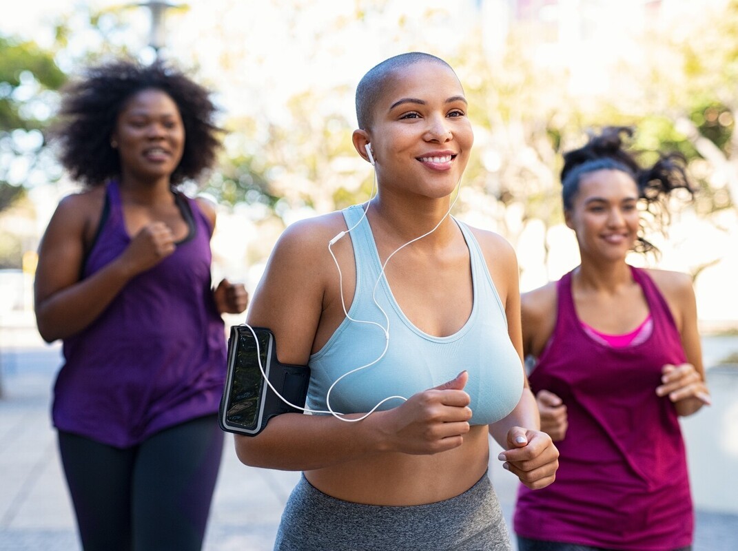 group of women going on an intermediate-level run for weight loss in a quiet neighborhood with trees in the background