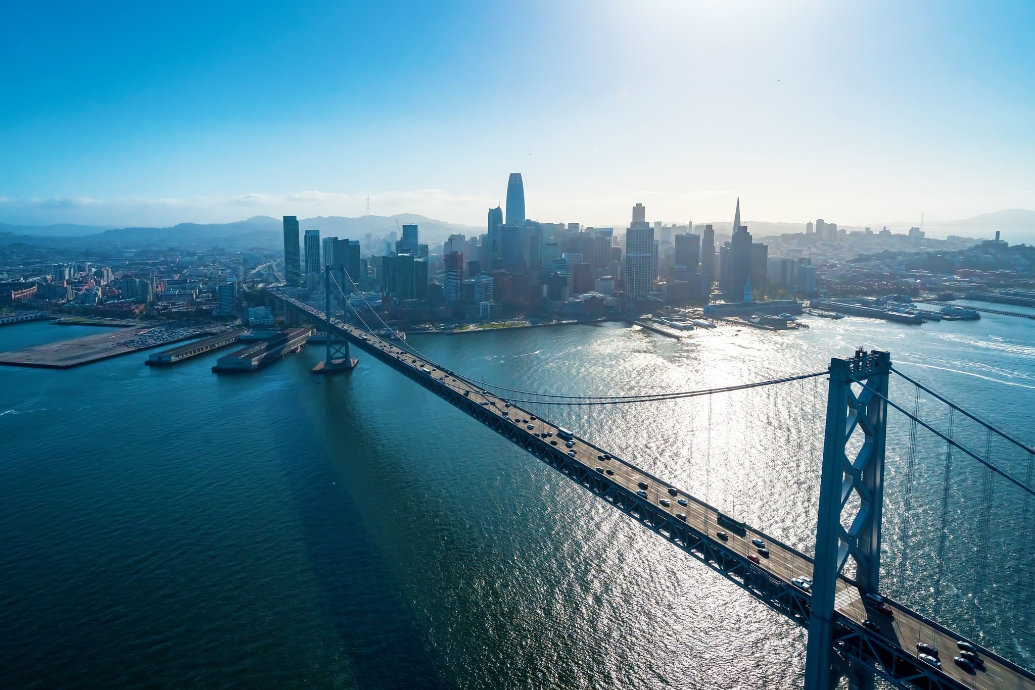 Aerial view of the San Francisco-Oakland Bay Bridge leading into the city skyline over the water.