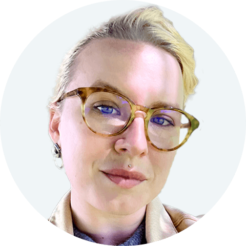 Headshot of Hannah Rogge, a light-skinned person with blonde hair pulled back, wearing round brown glasses and smiling slightly.