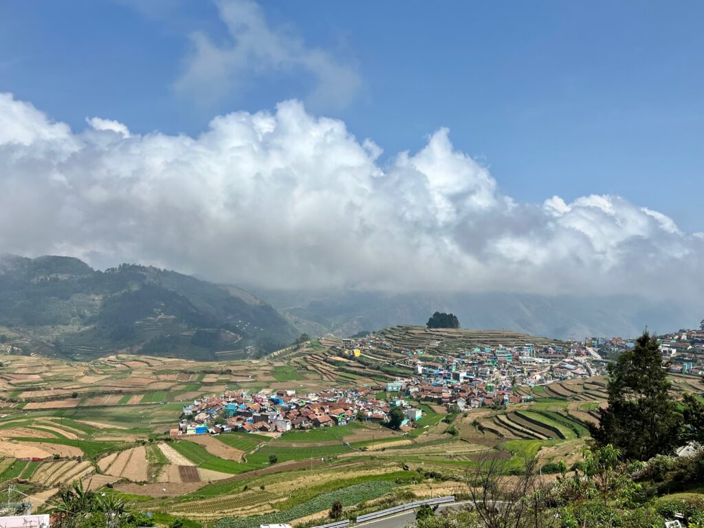 Poombarai village view with terrace farmlands and hills with fog beyond it.