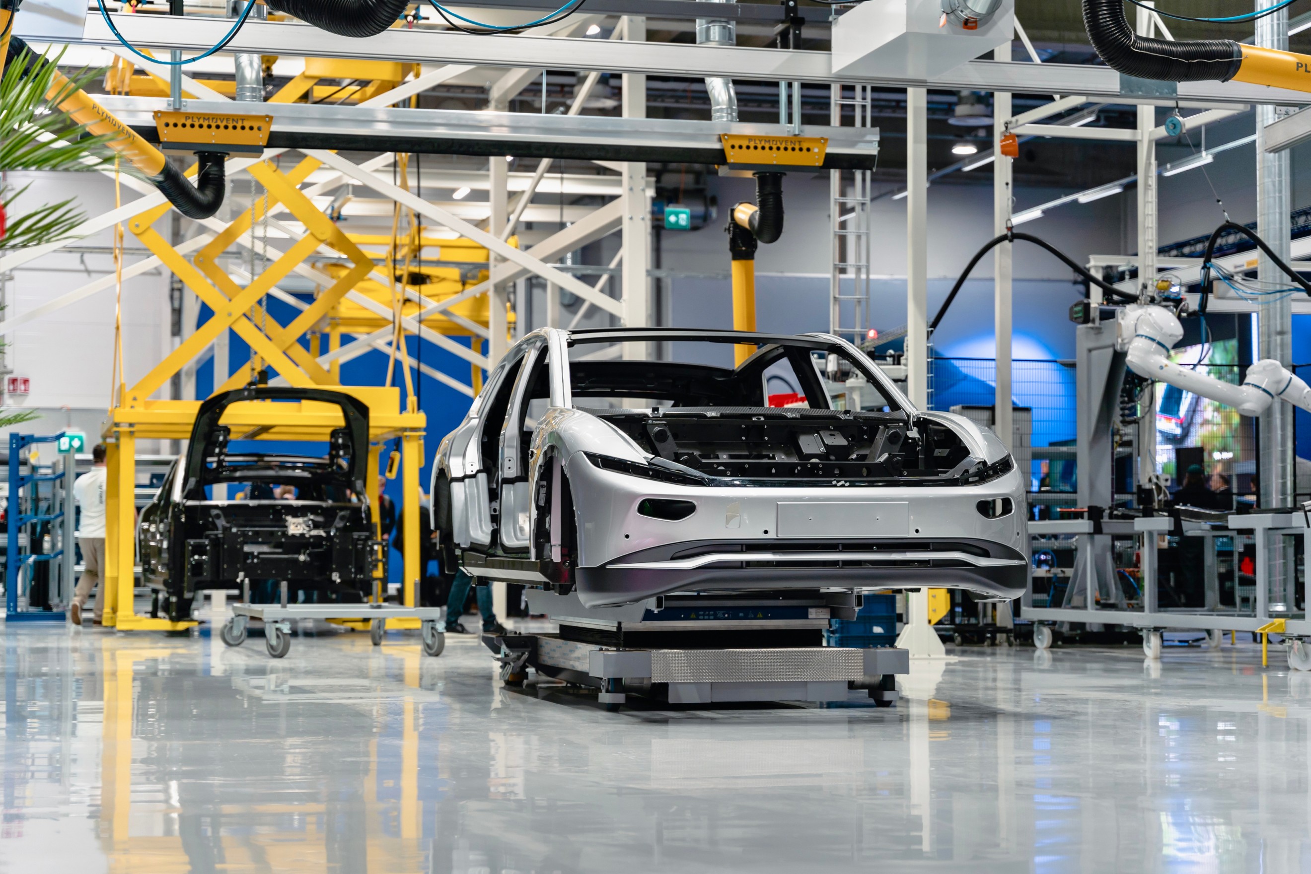 Lightyear 0 electric car inside the production facility in Uusikaupunki, Finland, with a sleek aerodynamic shape, surrounded by industrial equipment and assembly lines, showcasing its innovative solar-powered design in the manufacturing phase.