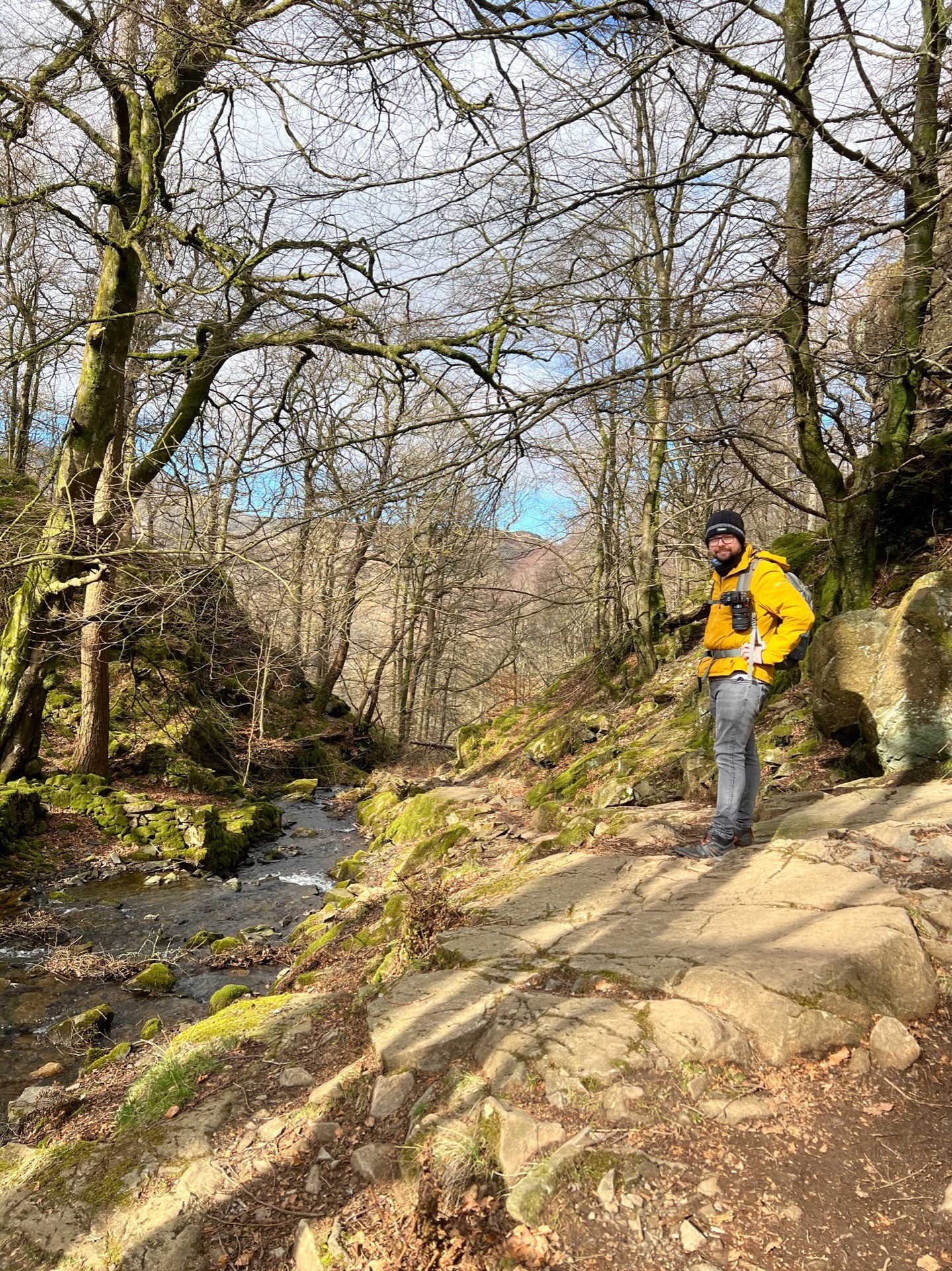 Martin stood next to a tumbling brook. The forest trees around have no leaves on.