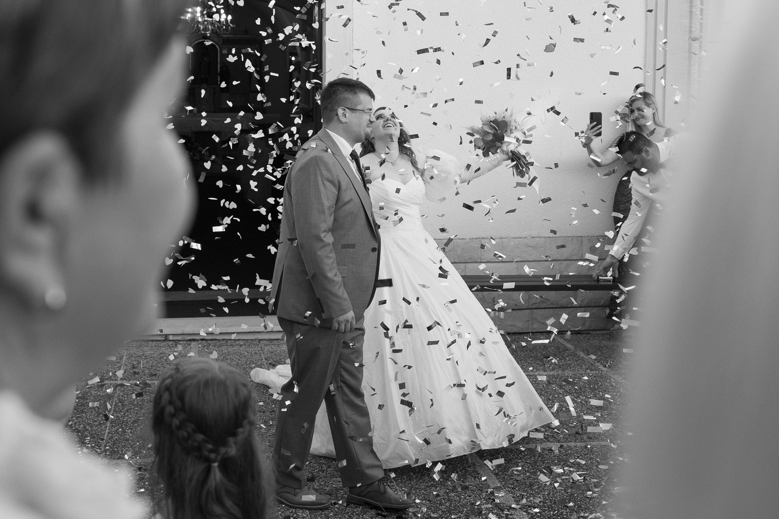 Bride and groom walking unfront of an old church with confetti falling all around them