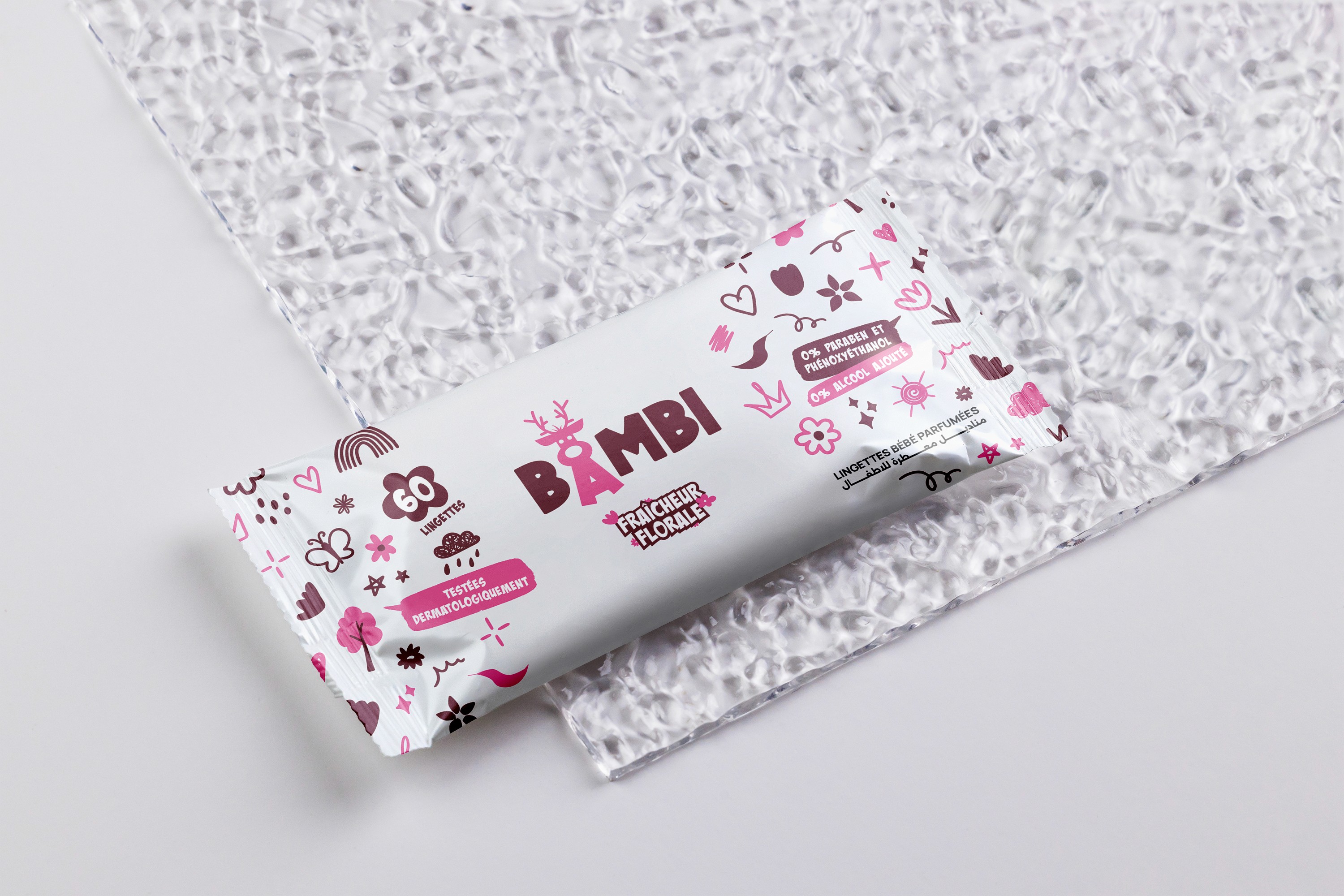 Person wearing black clothing carrying a black tote bag with a green globe-like geometric symbol, standing against a concrete wall in sunlight and shadow.