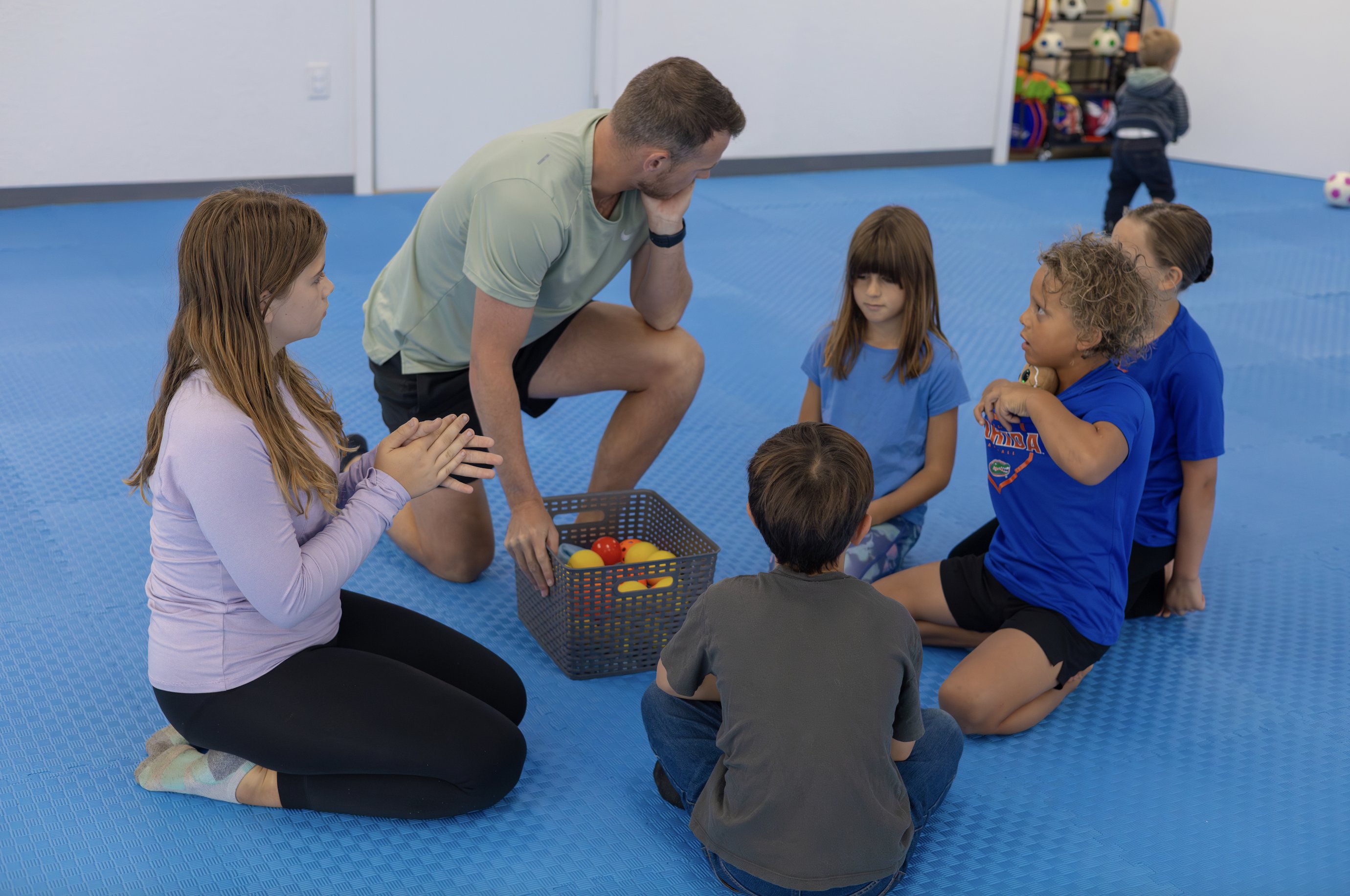 Children sitting in a safe open space with a teacher during a group activity