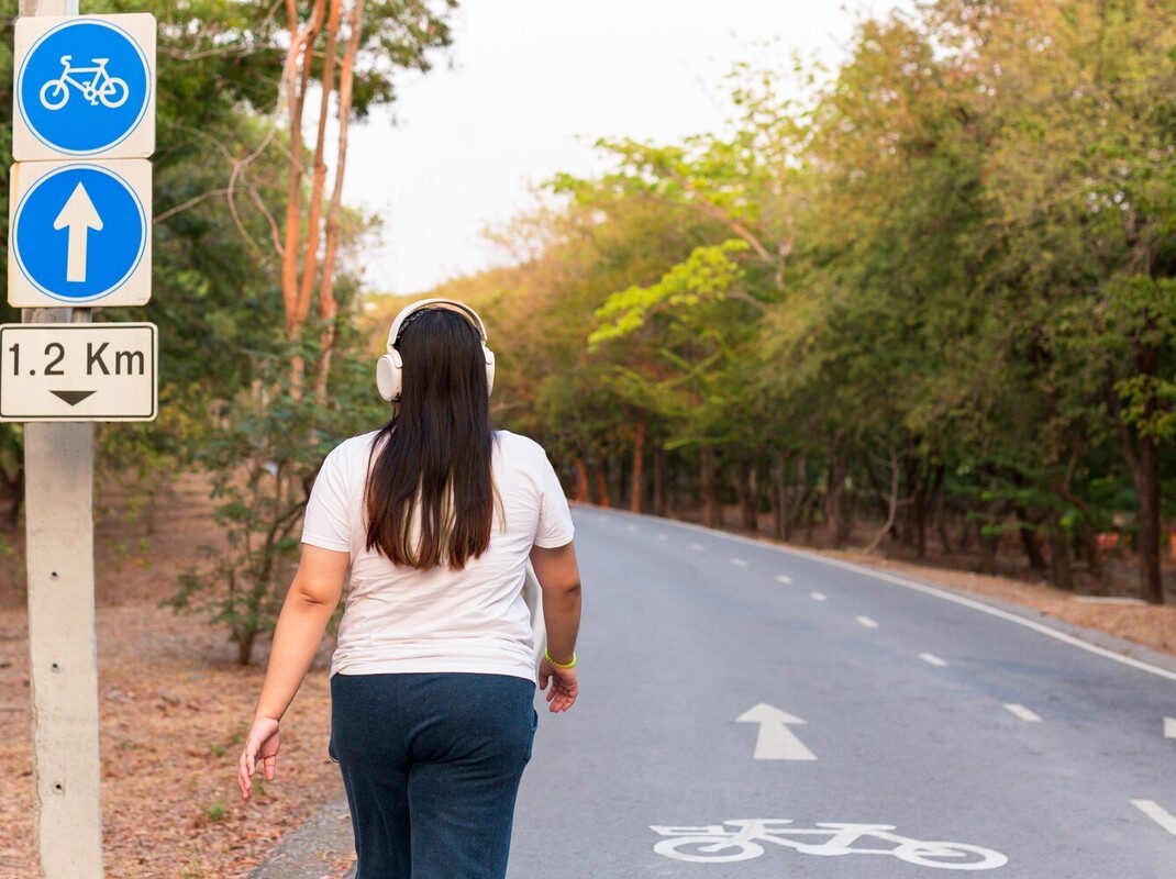 woman wearing headphones while going for a walk outside to supplement her weight loss yoga