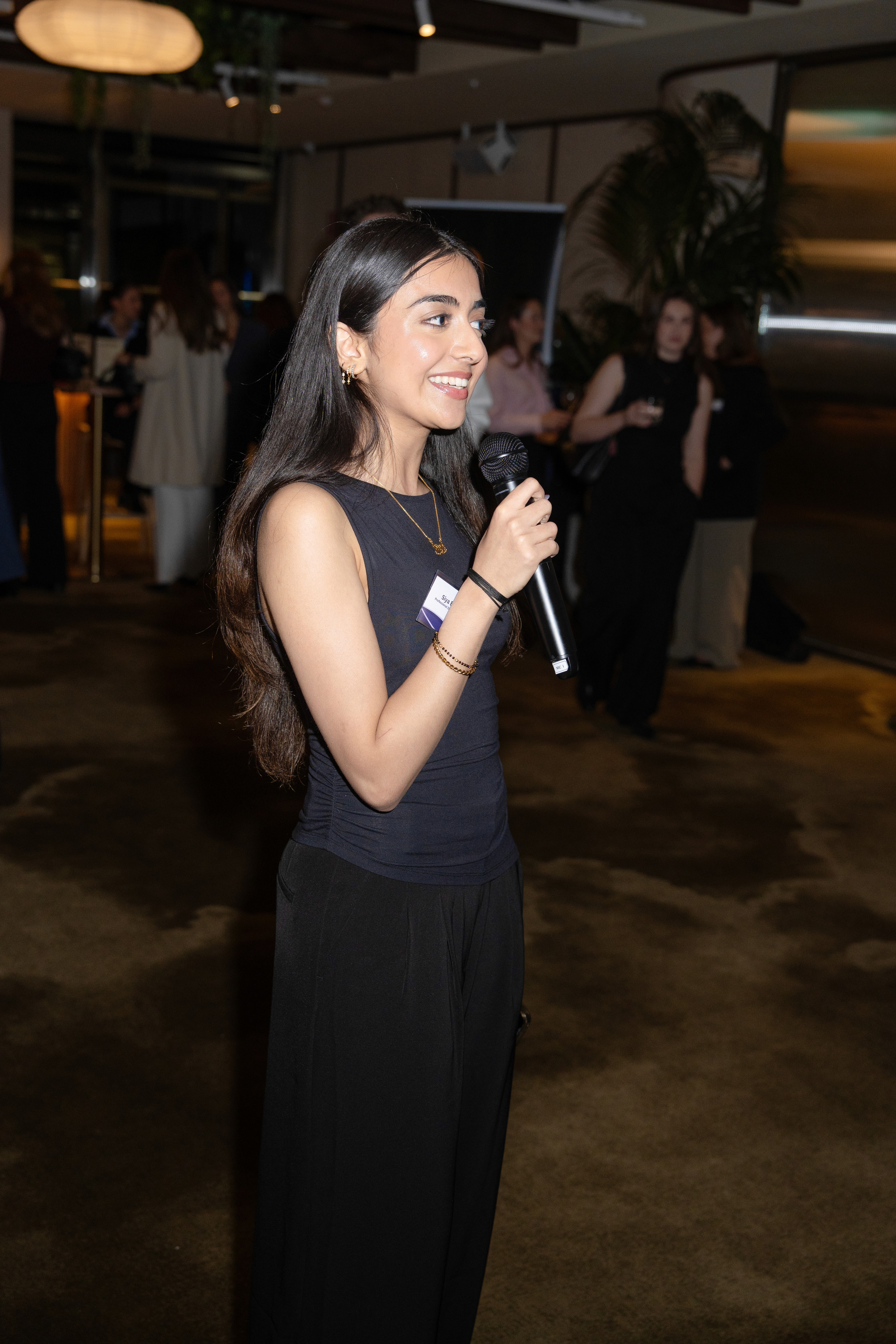 A person with long hair stands against a bright, hazy background, reaching out with one hand.