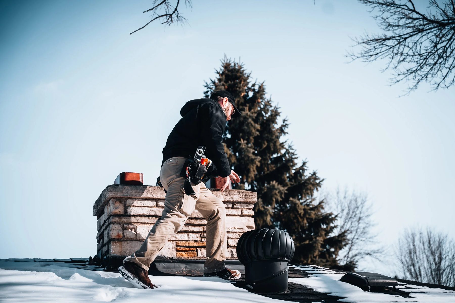 HomeSight inspector checking a chimney on a snowy Minnesota roof