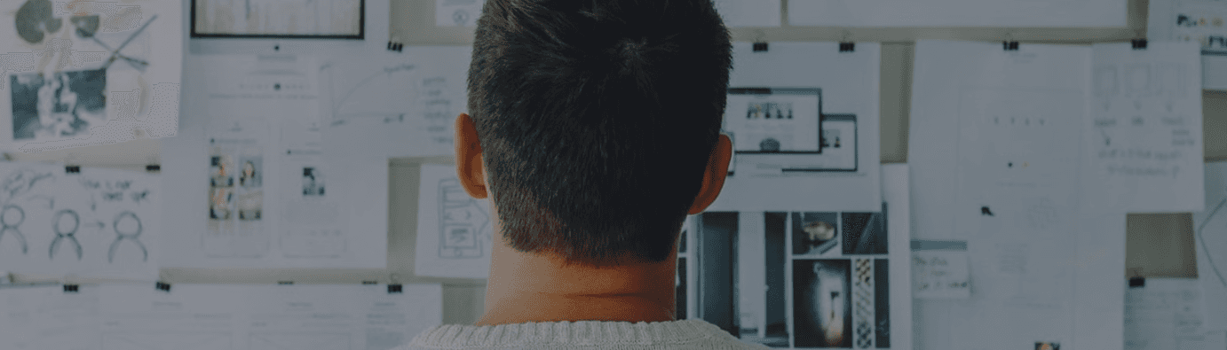 Person von hinten vor einem Whiteboard mit Skizzen und Konzeptnotizen in einem Workshop-Setting