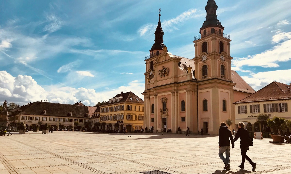 Marktplatz Ludwigsburg mit der Stadtkirche im Hintergrund und einem Pärchen, das Hand in Hand über den Platz läuft