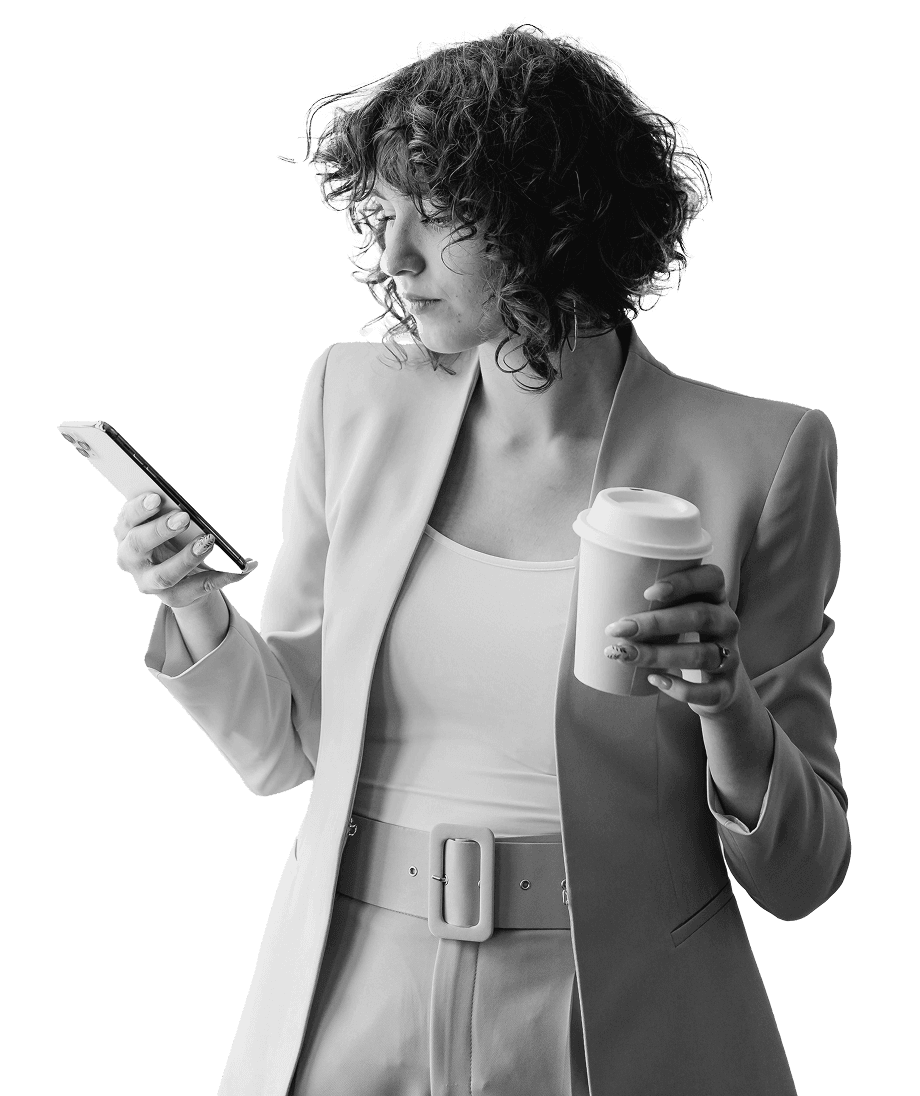 A professional woman in a business suit holding a smartphone and a coffee cup, appearing focused, symbolizing modern finance and simple stocks trading.