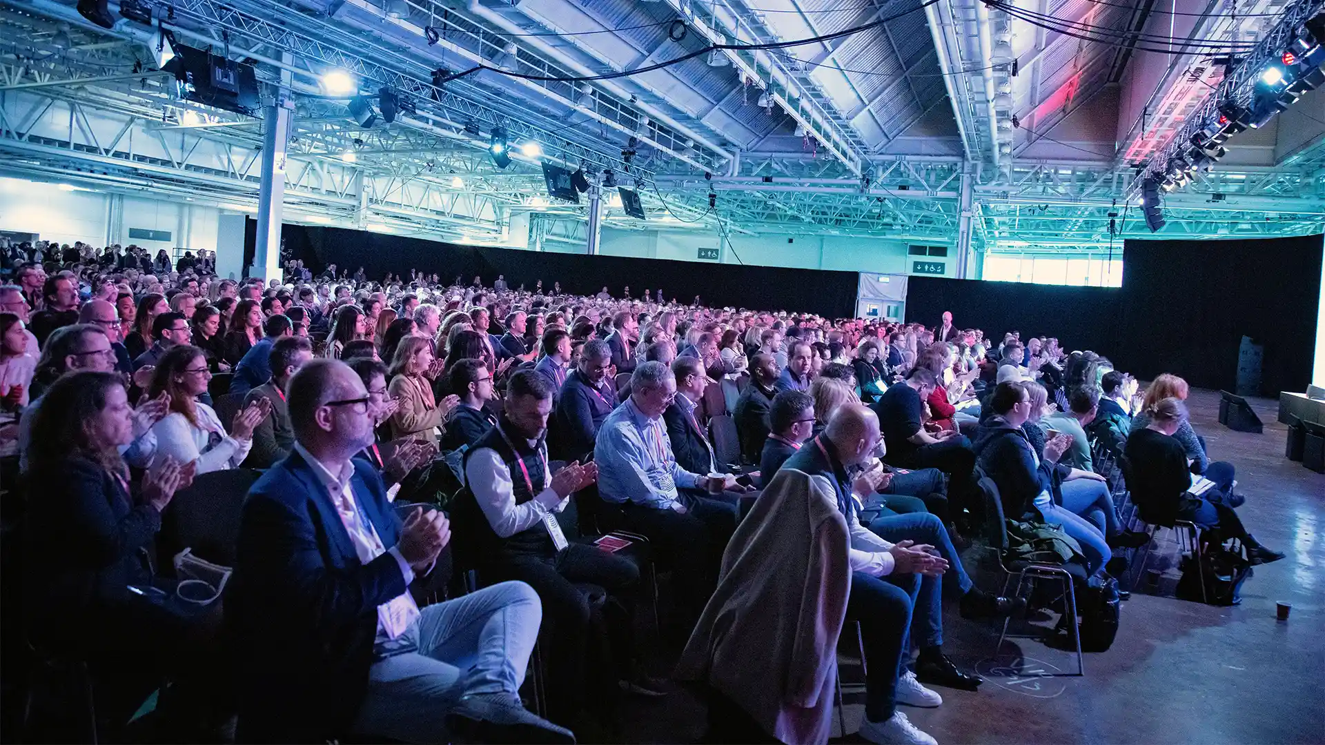 Wide view of a large seated audience attending a conference session at Olympia London.