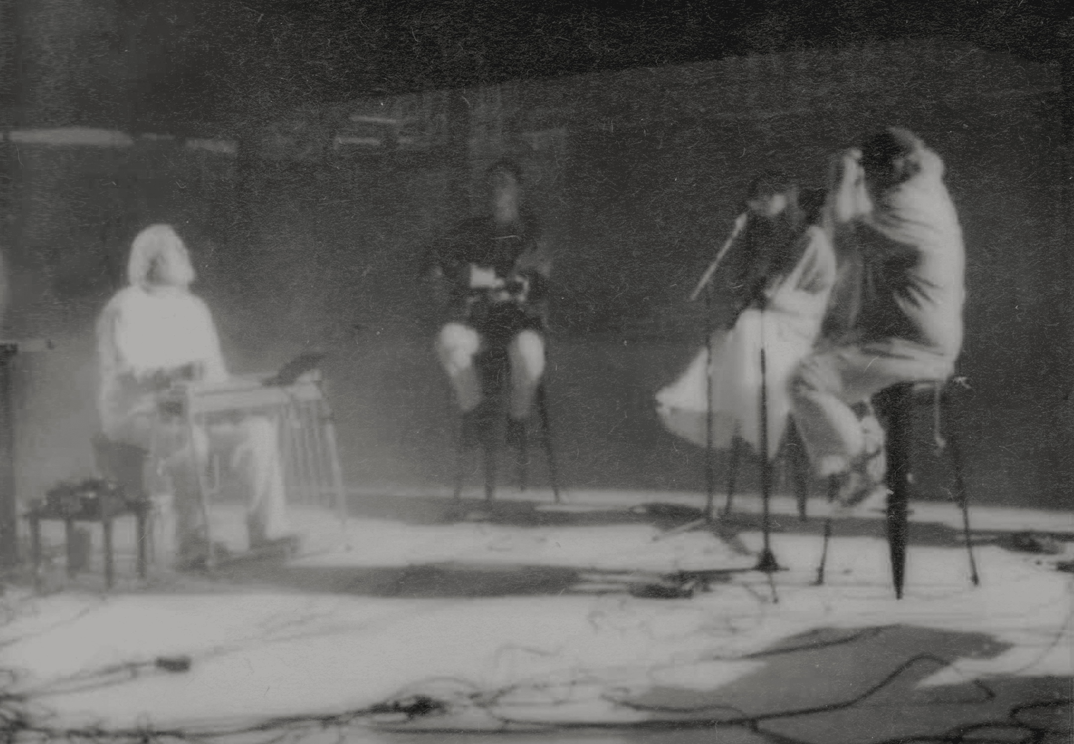A performer sits at a piano under a single spotlight in a darkened space, creating an intimate atmosphere.