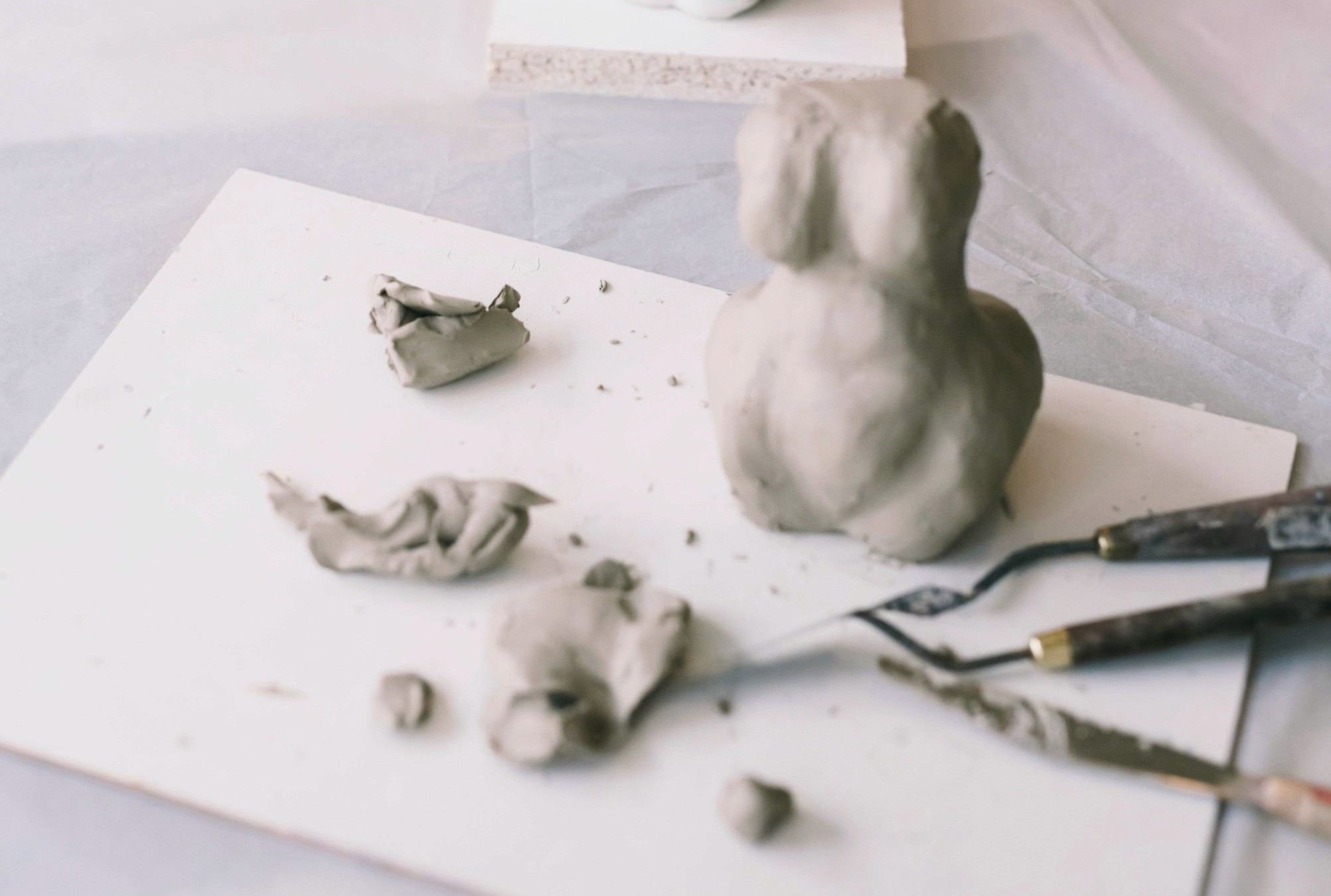 Cours de sculpture modelage céramique à Guérande : figurine en argile grise en cours de création avec outils