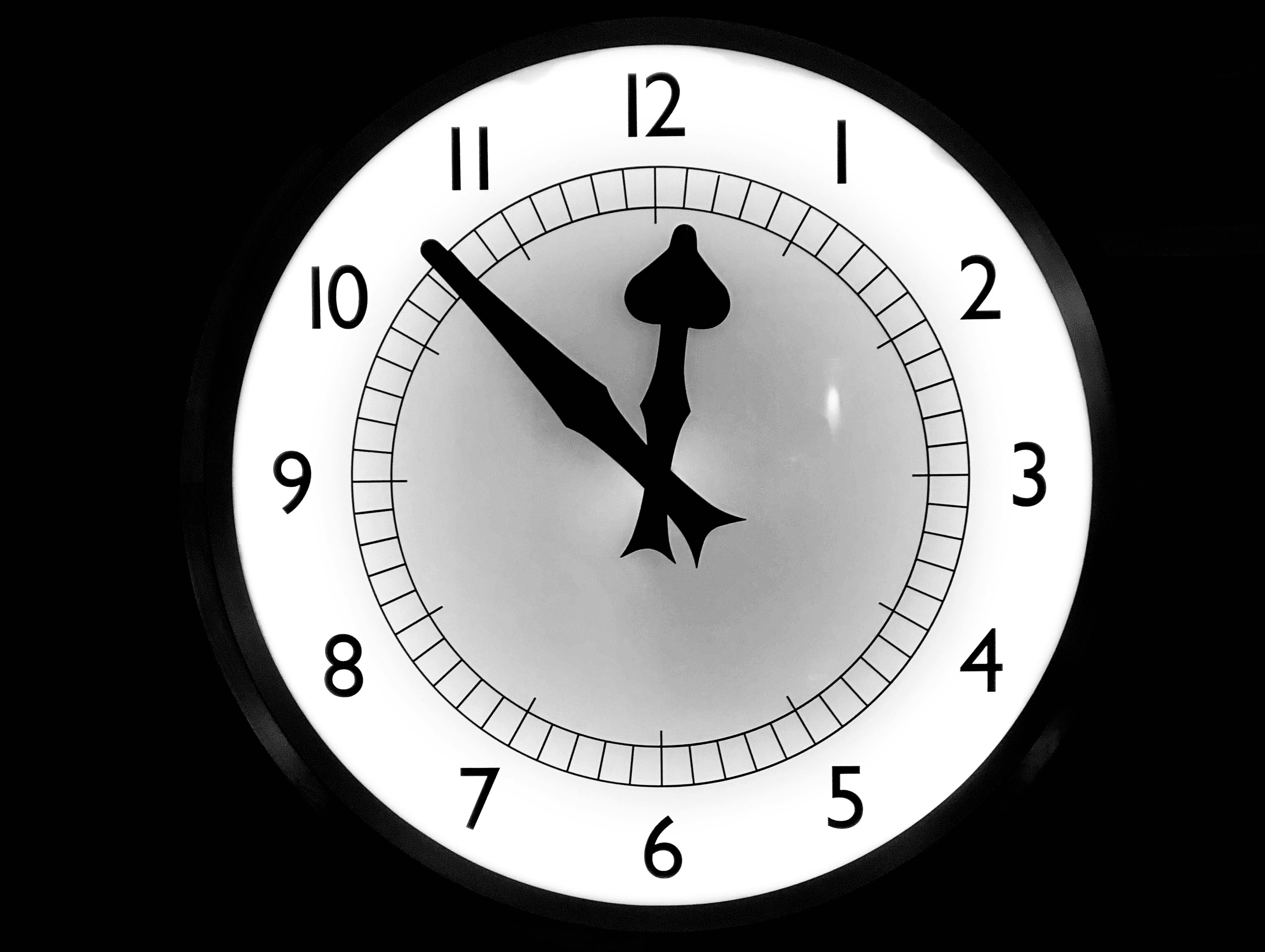 a white clock with black numbers on a black background