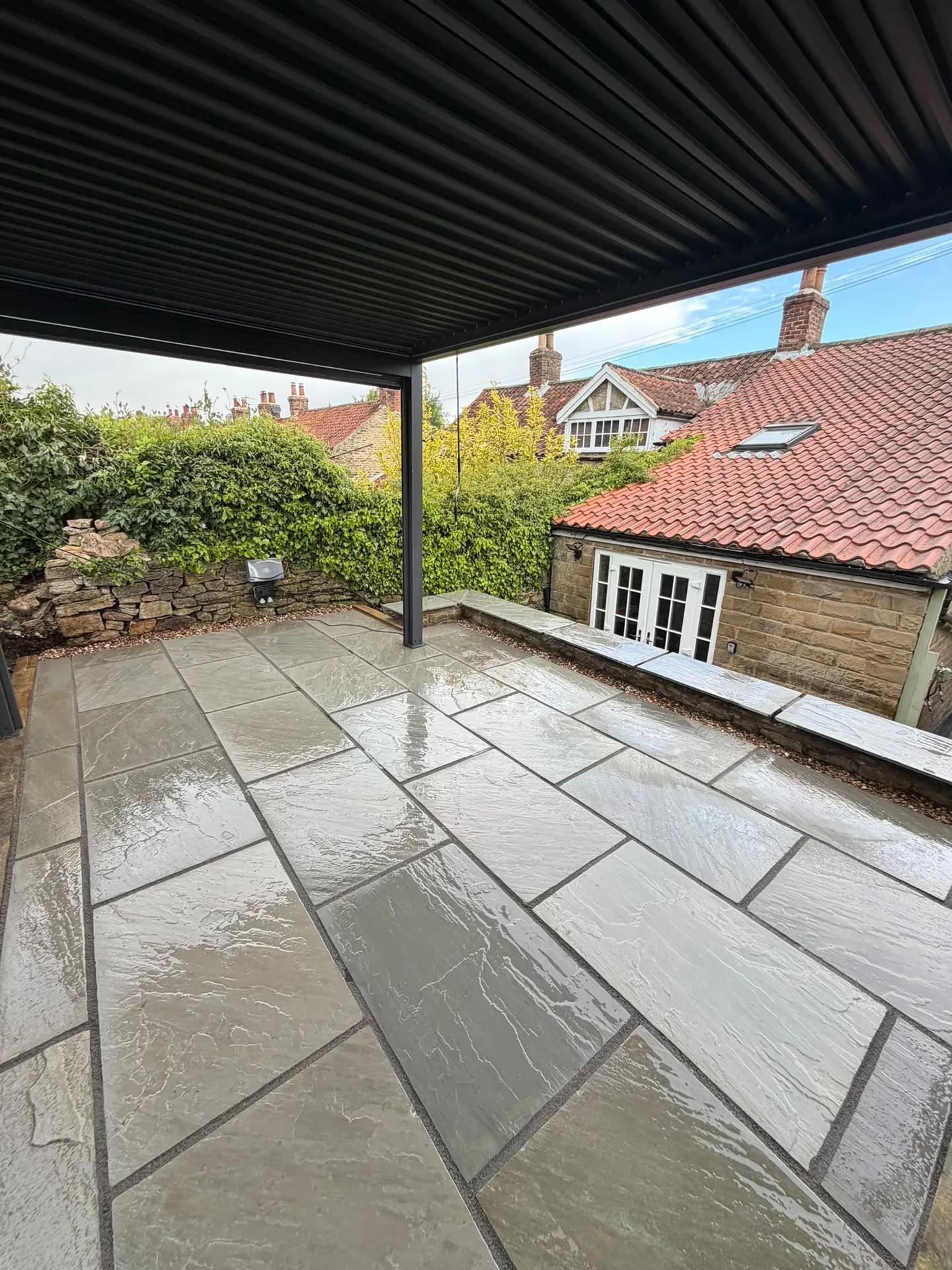 Finished Indian stone patio beneath a black pergola in York