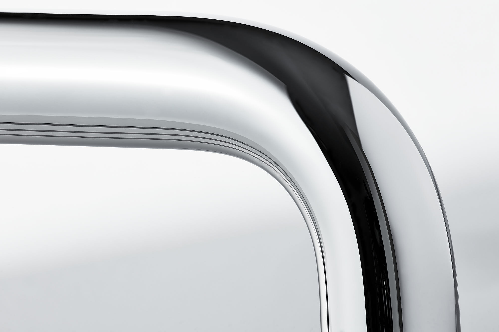 Close-up of sleek modern chrome chair arm with reflective surface.
