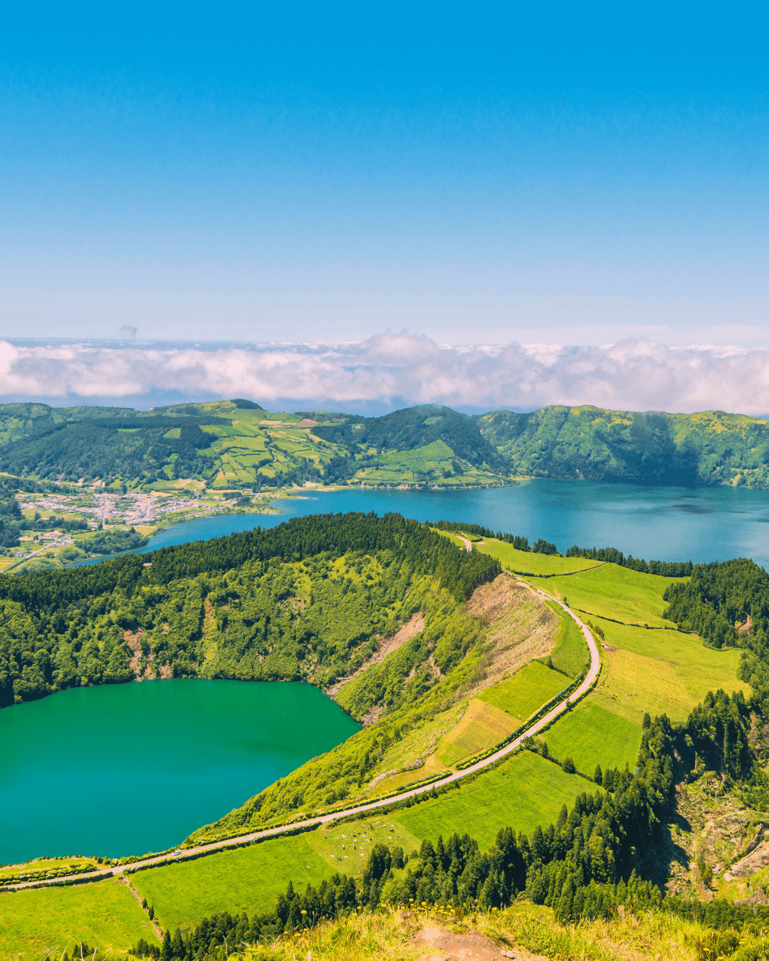 A smiling woman with her arms crossed, standing against a dark green background. She has long, dark hair.