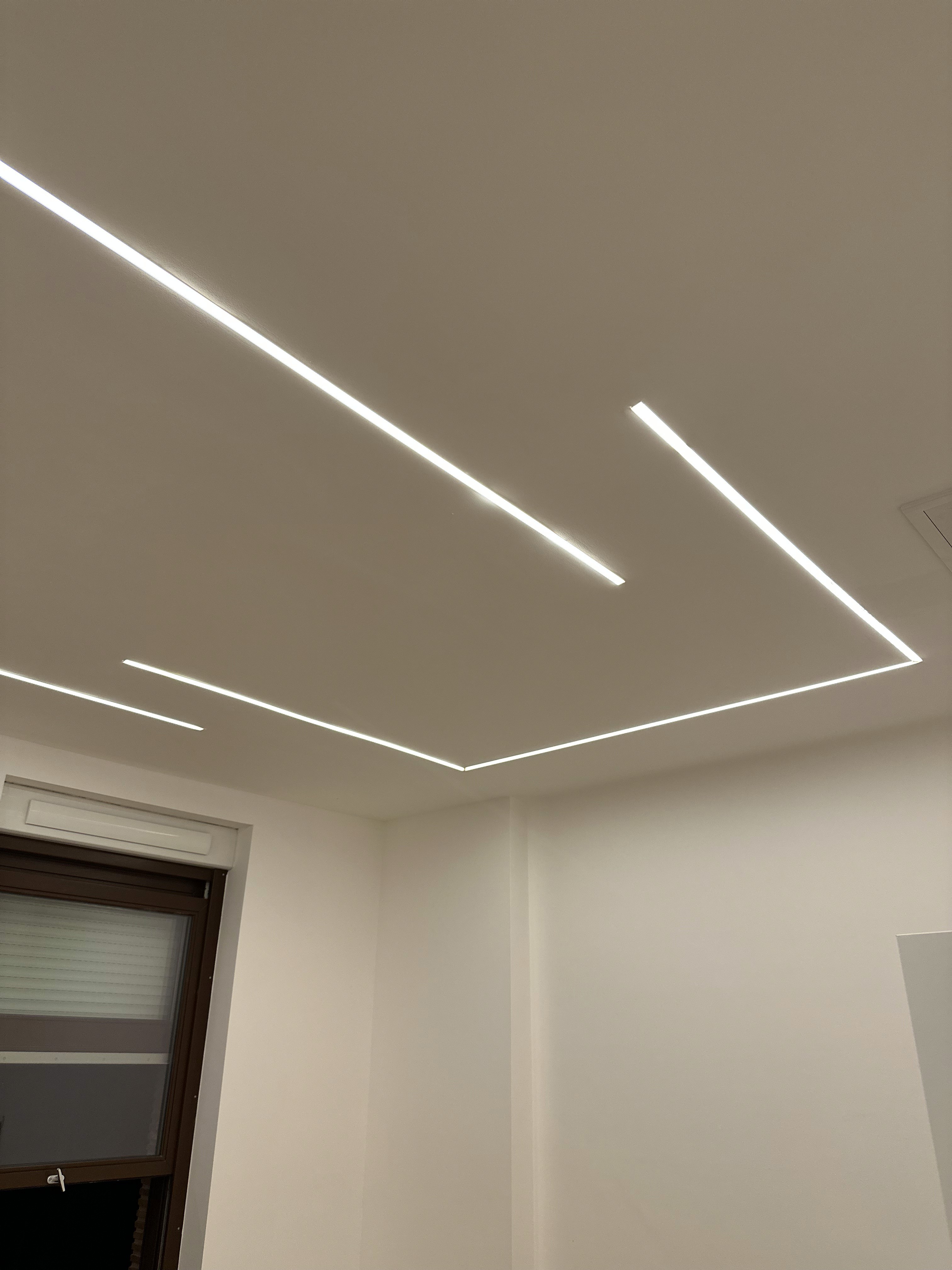 Modern living room with abstract art, beige sectional sofa, indoor plants, and large windows.