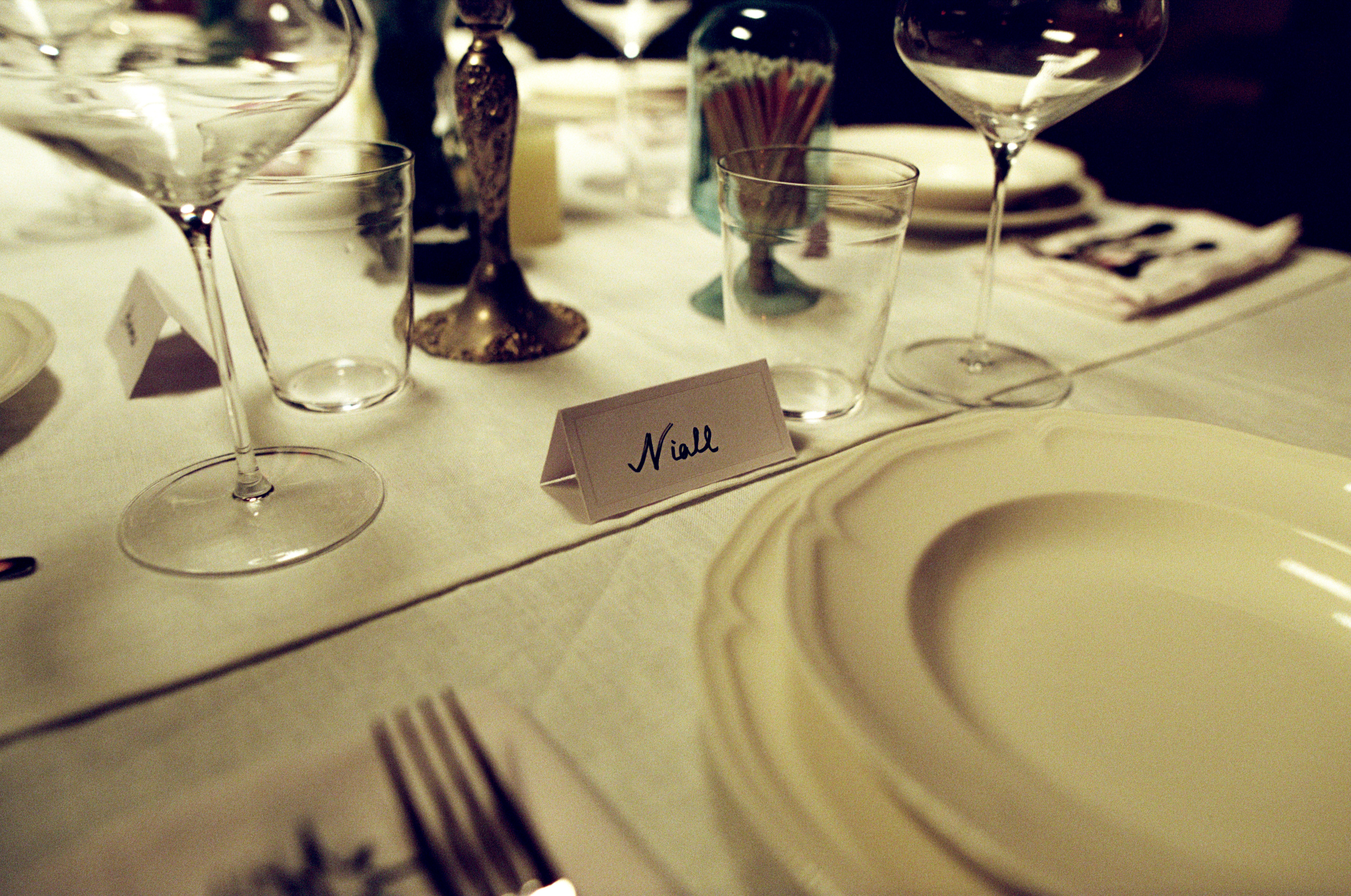 A decorated table with a floral tablecloth, featuring two vases of flowers and several blank white cards displayed behind.