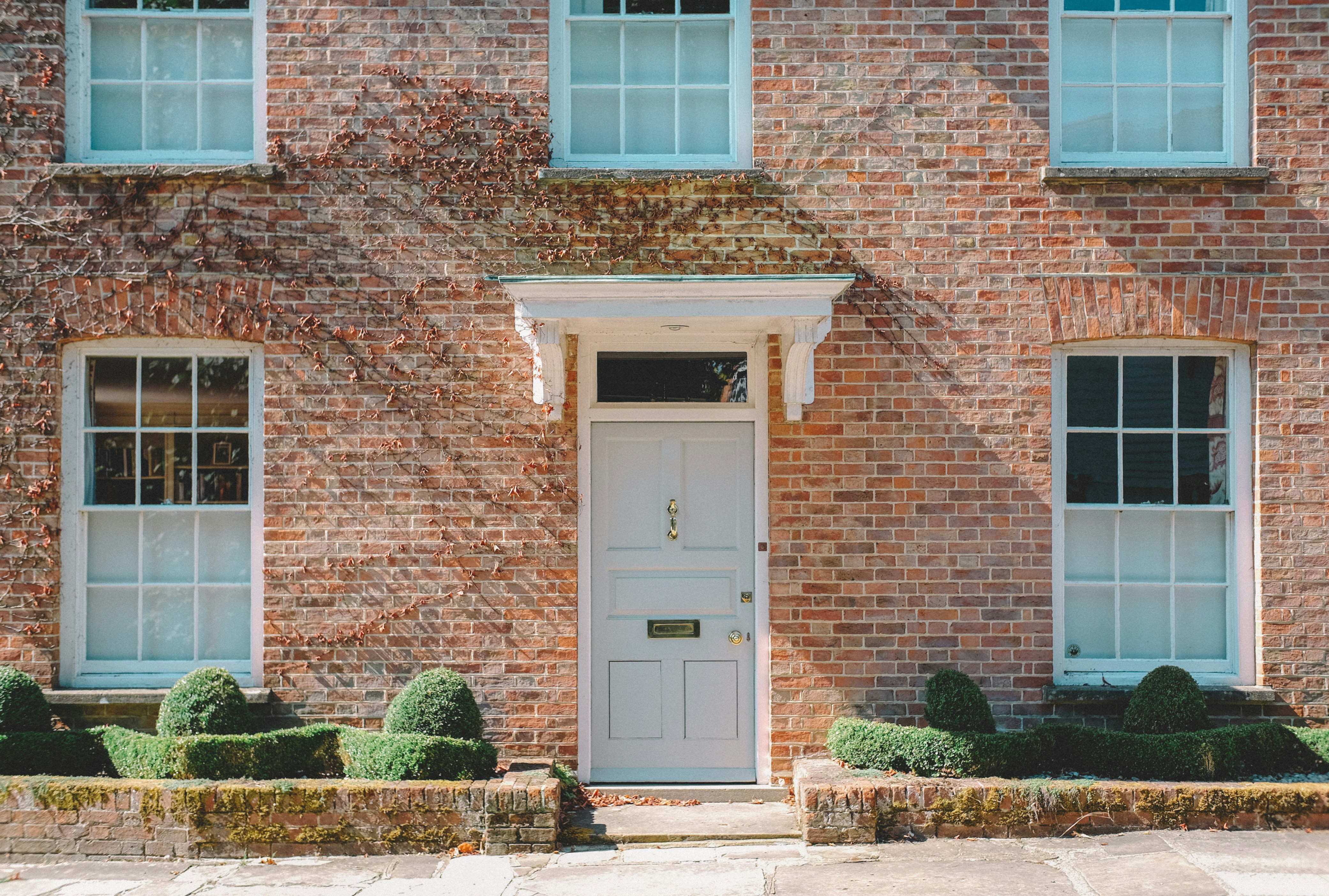 Brick house with a white front door and small hedges to the left and right
