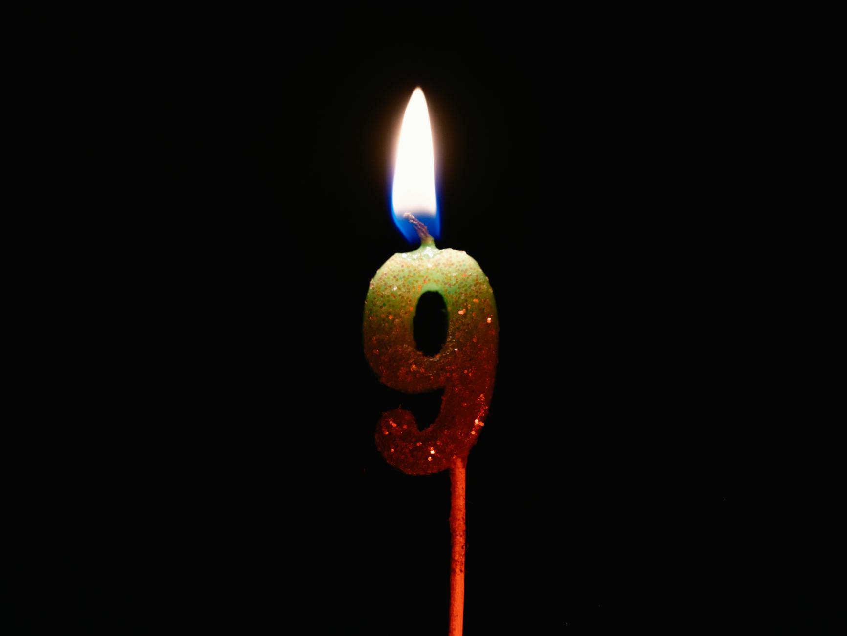 Burning number nine candle against a dark backdrop, perfect for birthdays or anniversaries.