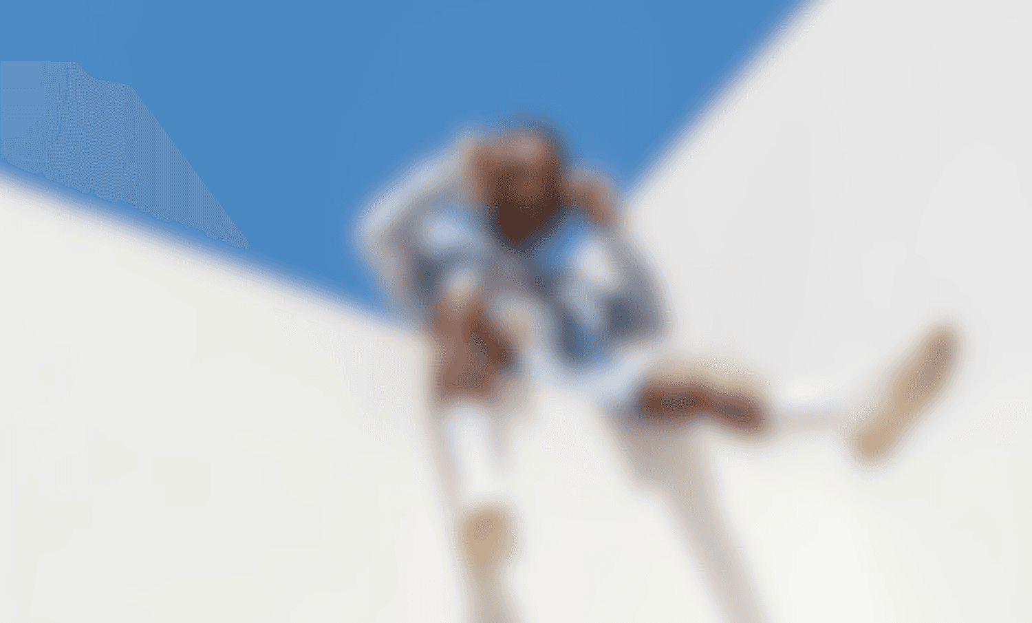 Blurred close-up of a green parrot with yellow and orange feathers, water droplets.