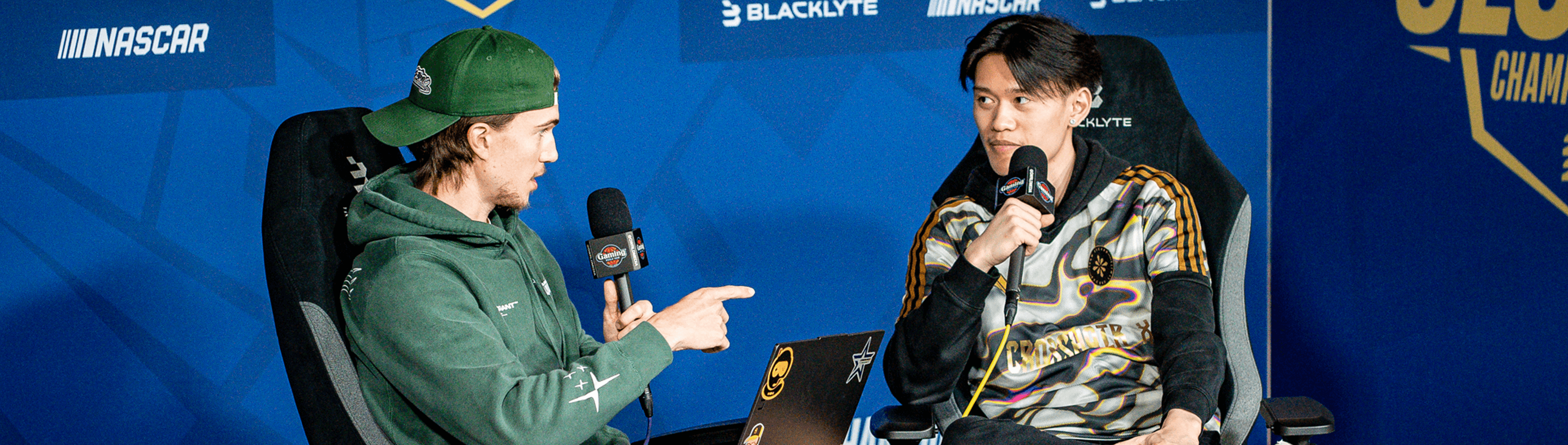 Two esports commentators speaking into microphones on a broadcast desk