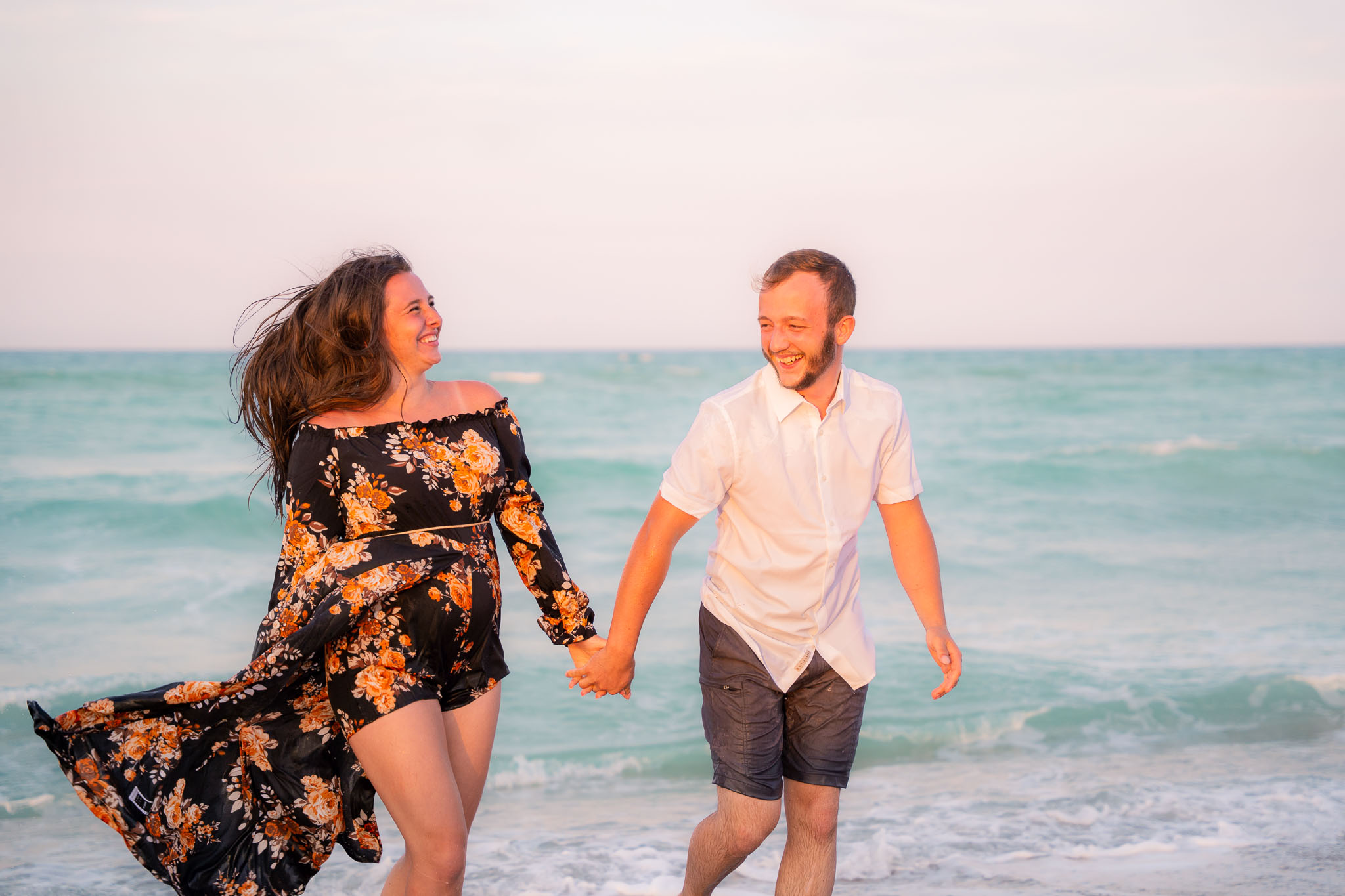  a couple holding hands jotting across the beach