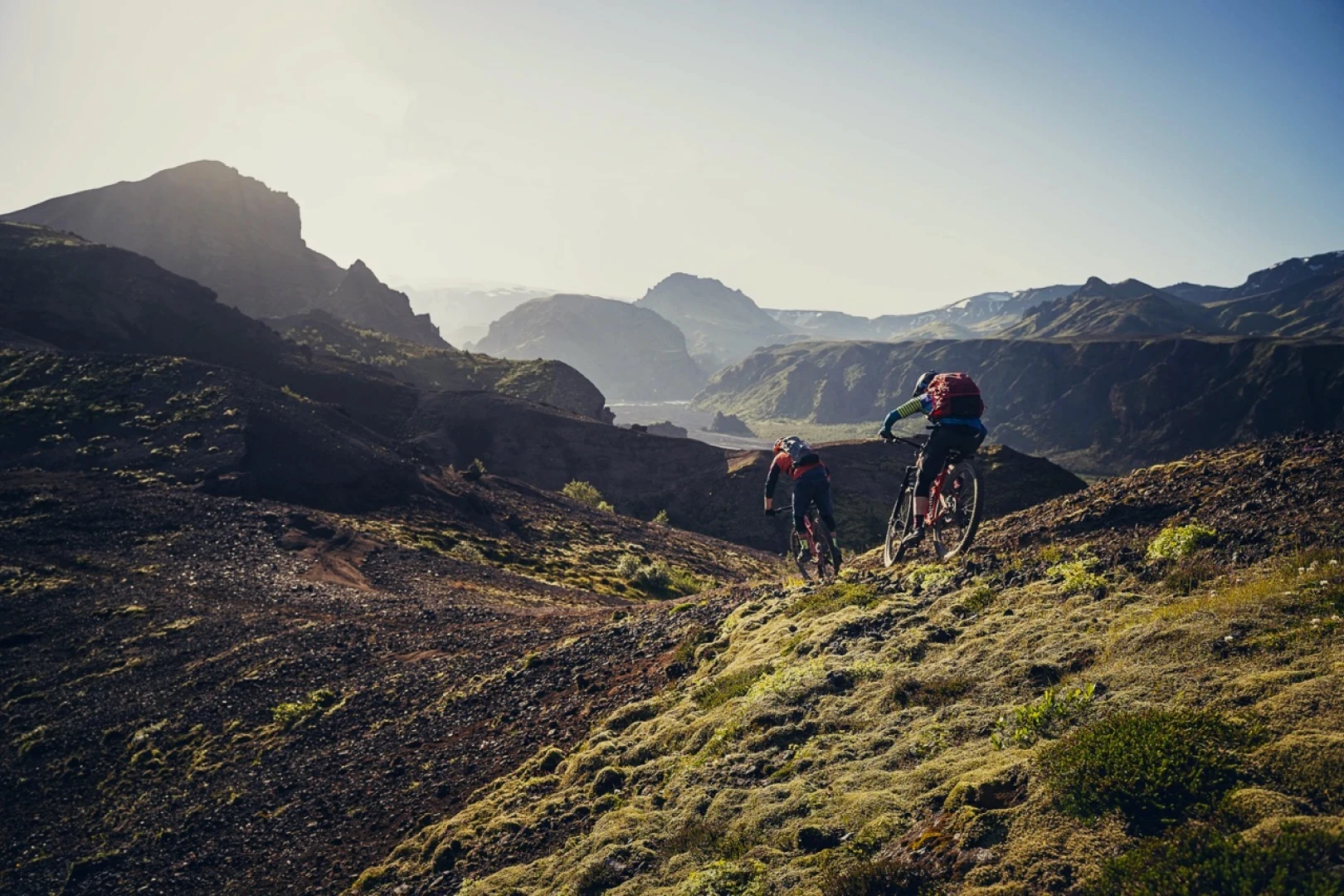 Big Landscapes by sunset with two men riding away from camera into the mountains