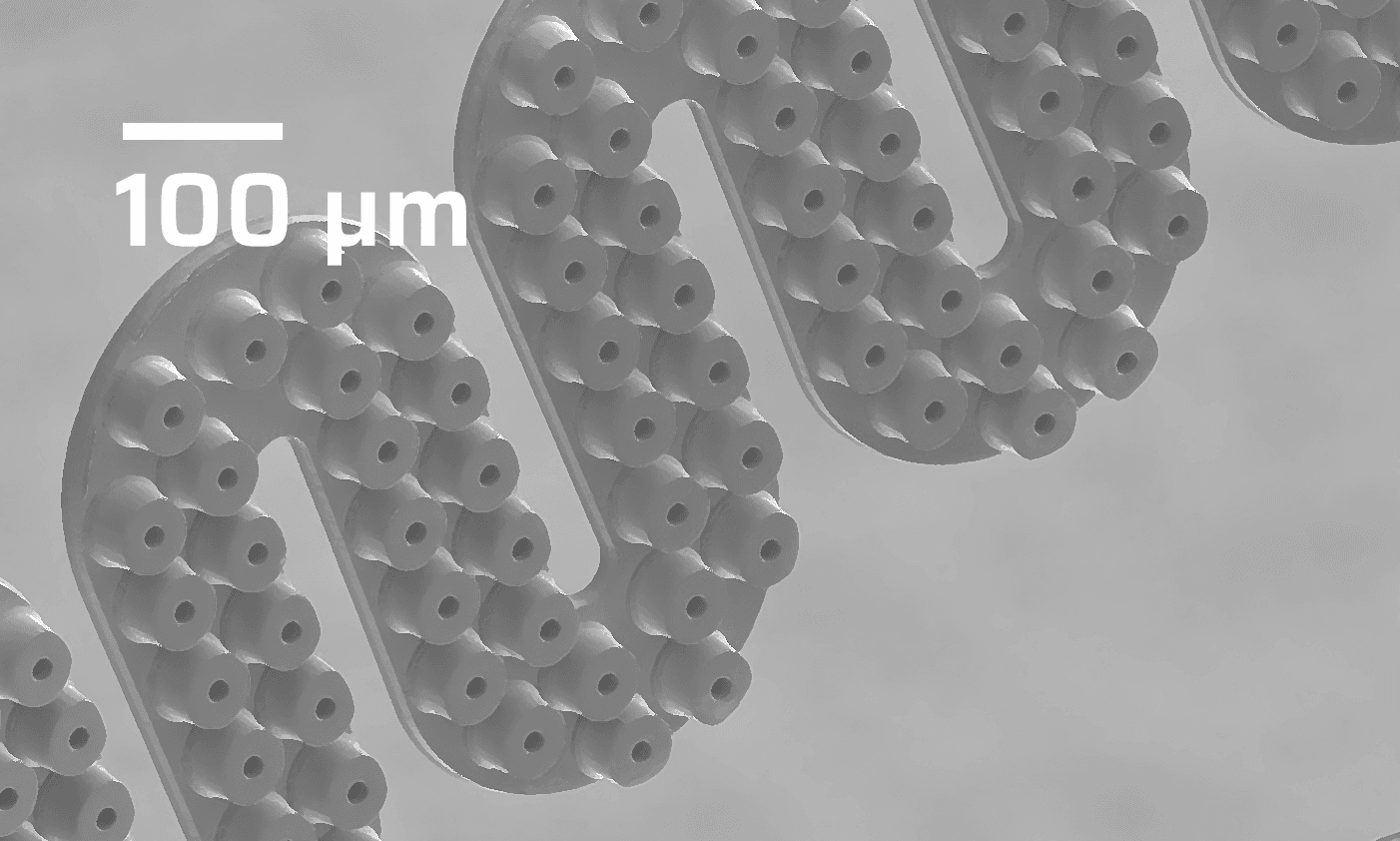Person in lab gloves holding a square semiconductor wafer with patterned microstructures in a laboratory setting.