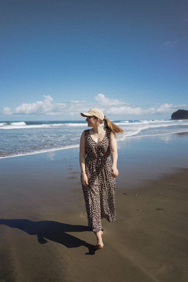Woman in a hat walking on a beach, showcasing selflove and serenity.