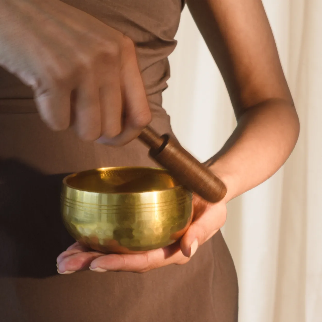 Hands playing a brass singing bowl