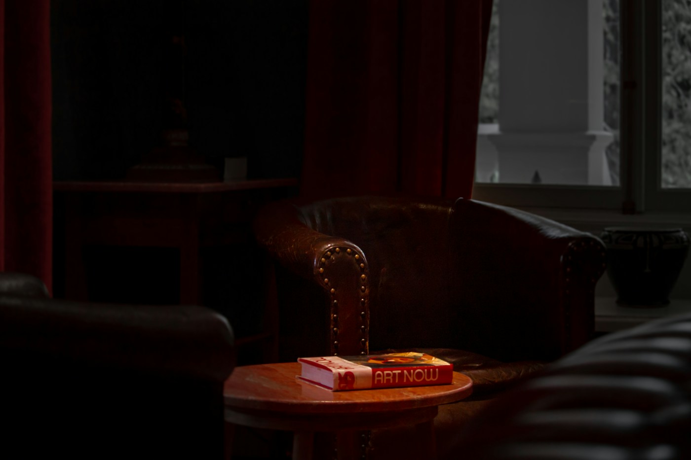 worn paperback book with bent spine resting on an armchair