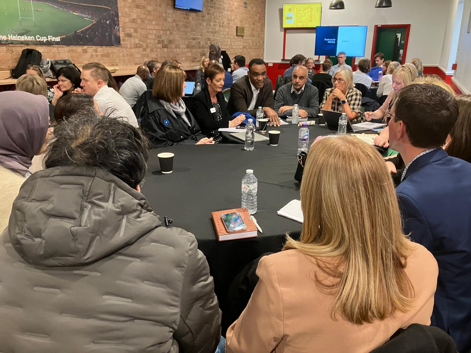 people sitting on chair in front of table while holding pens during daytime