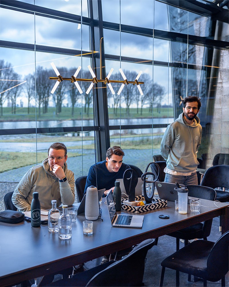 Drie individuen in een kantooromgeving met laptops en decor