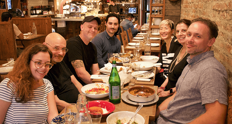 A photo showing people smiling at a restaurant table.