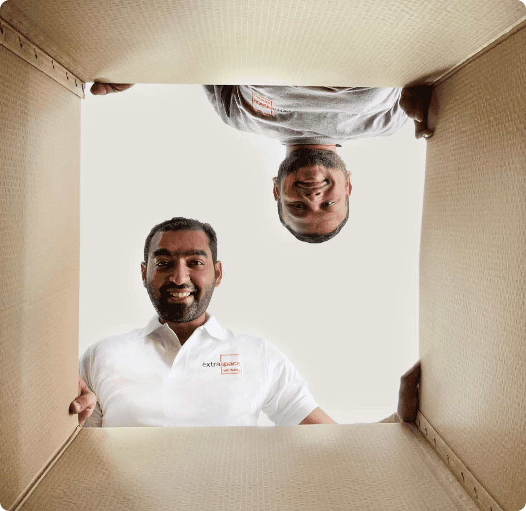 Two Extra Space international shipping handlers are looking into the inside of a box.