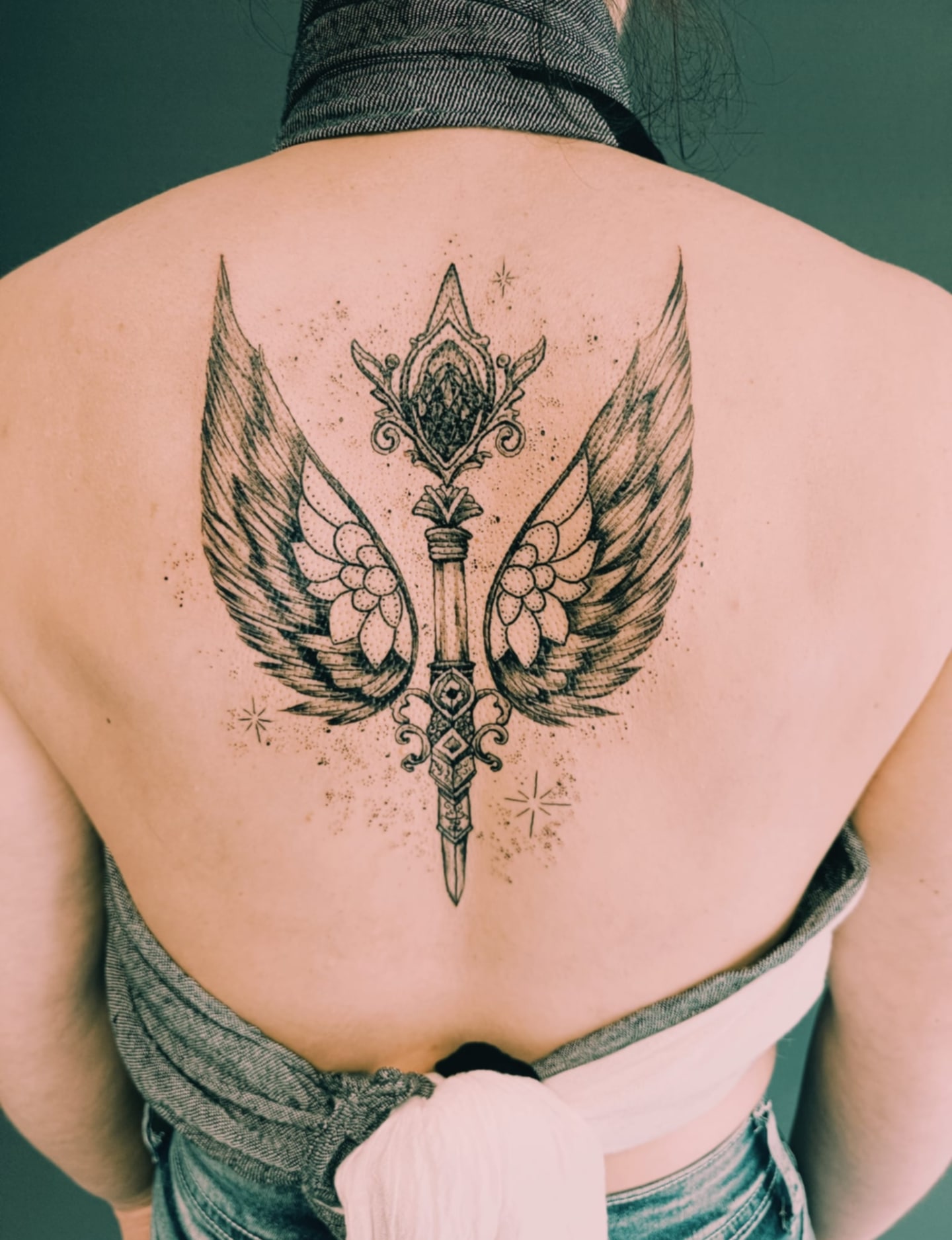 tatouage épée et deux ailes sur le dos d'un homme