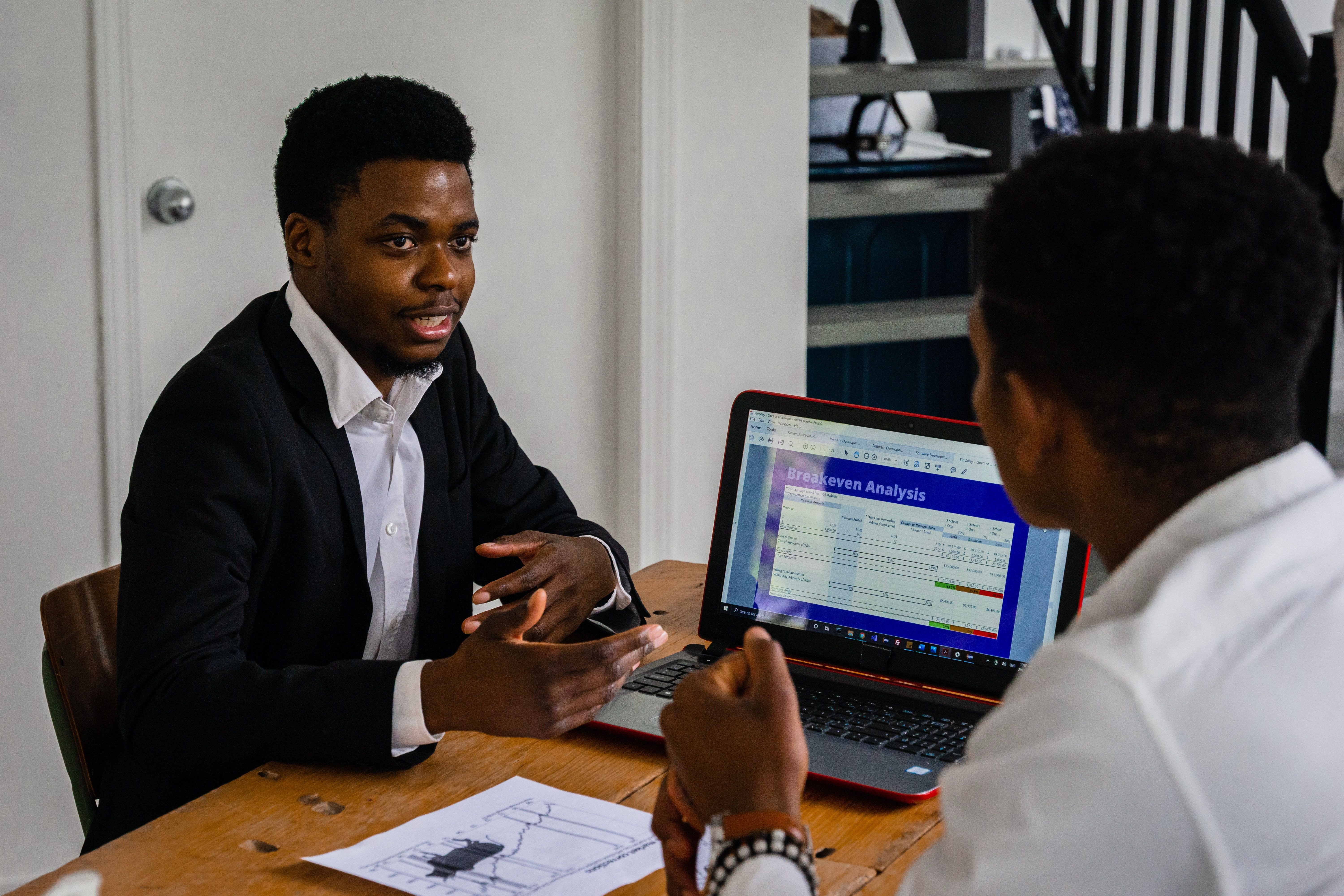 two-businessmen-engage-in-a-conversation-about-financial-strategies-with-a-lapto - pnw-production (pexels)