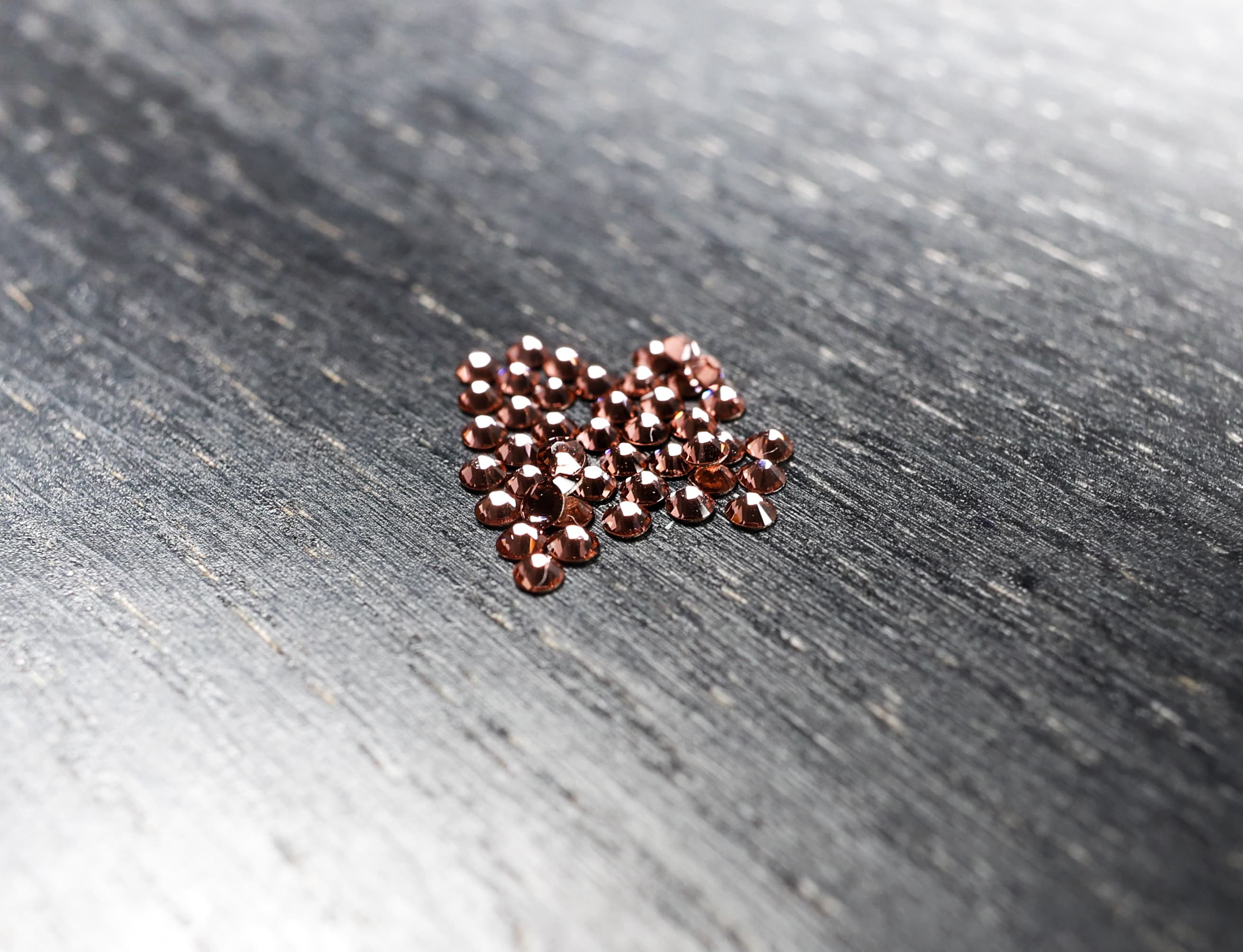 Rose Swarovski-Zahnsteine auf einem schwarzem Holzbrett