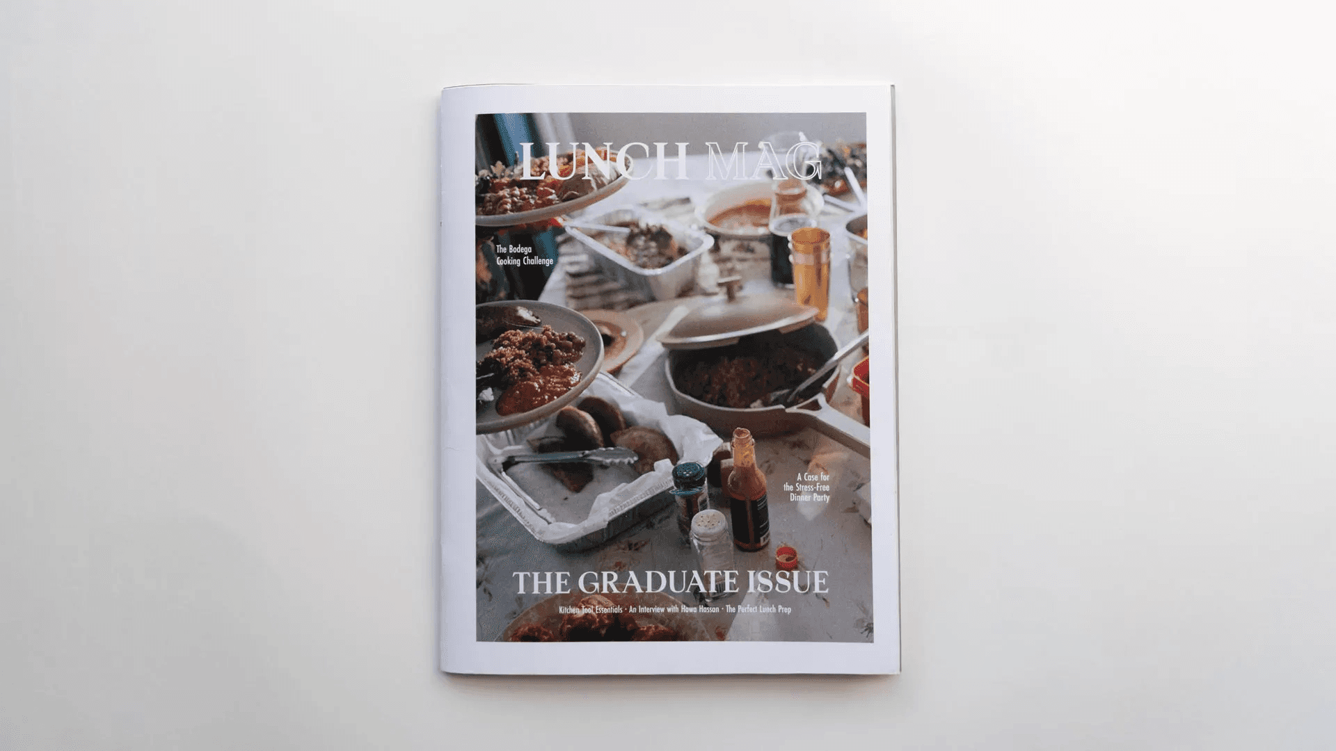 A visually appealing magazine cover titled "Lunch Mag" featuring various kitchen tools essential for cooking. The design highlights the theme of building your own kitchen and learning to prepare food, aimed at recent graduates.