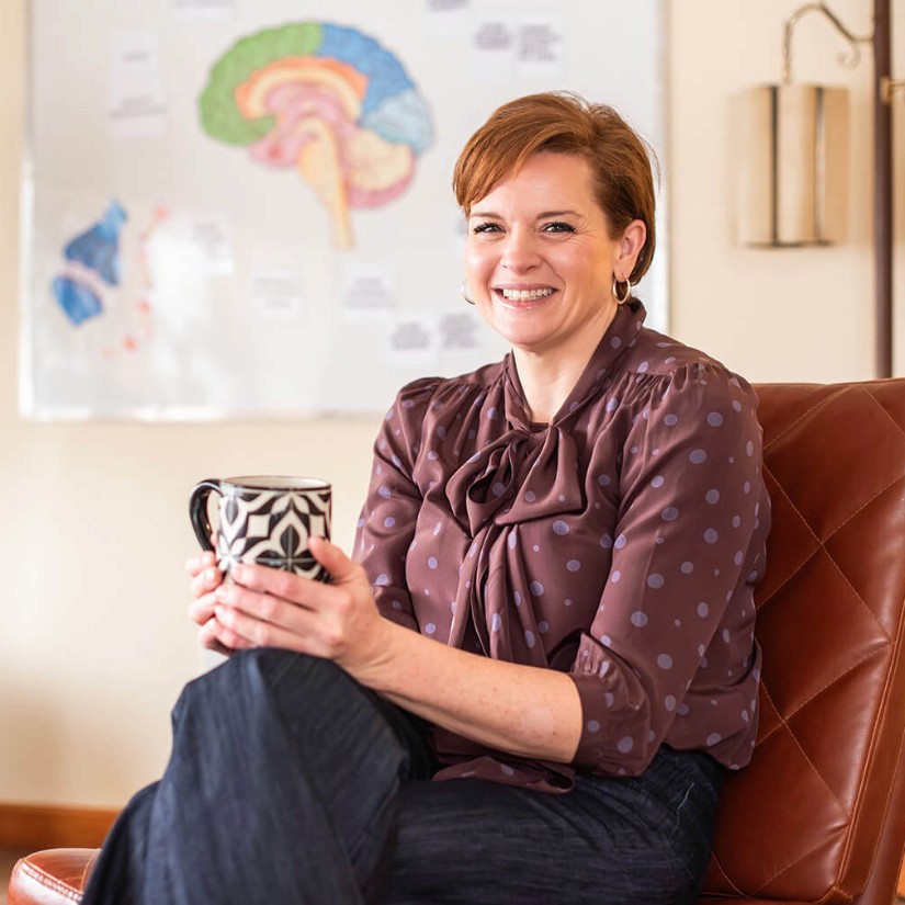 Jenny Chreptyk RN, CNP sitting in a chair with a mug in her hands