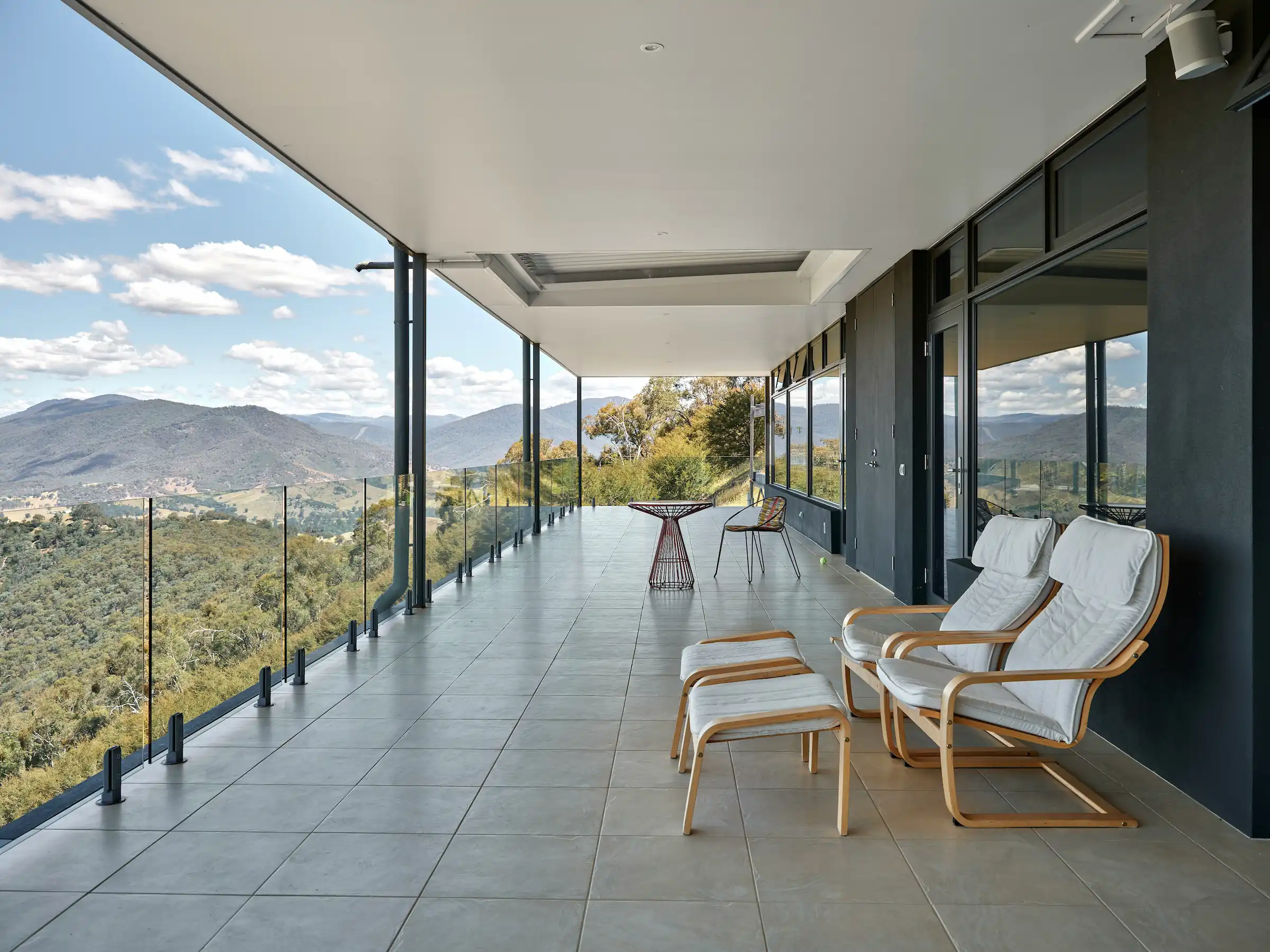 Minimalist living space featuring oak flooring, timber wall panels and panoramic windows with natural light.